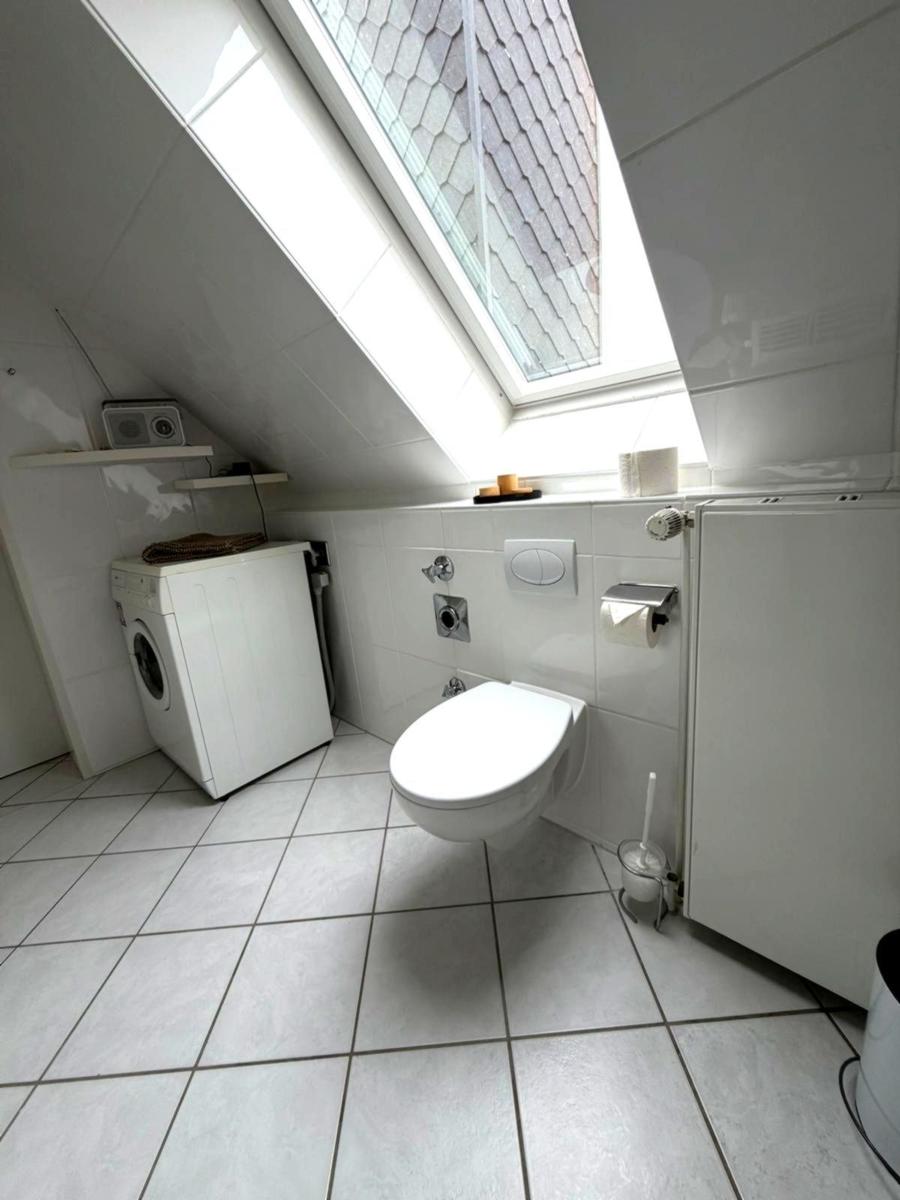 Badezimmer mit Toilette, Waschmaschine und Dachfenster.