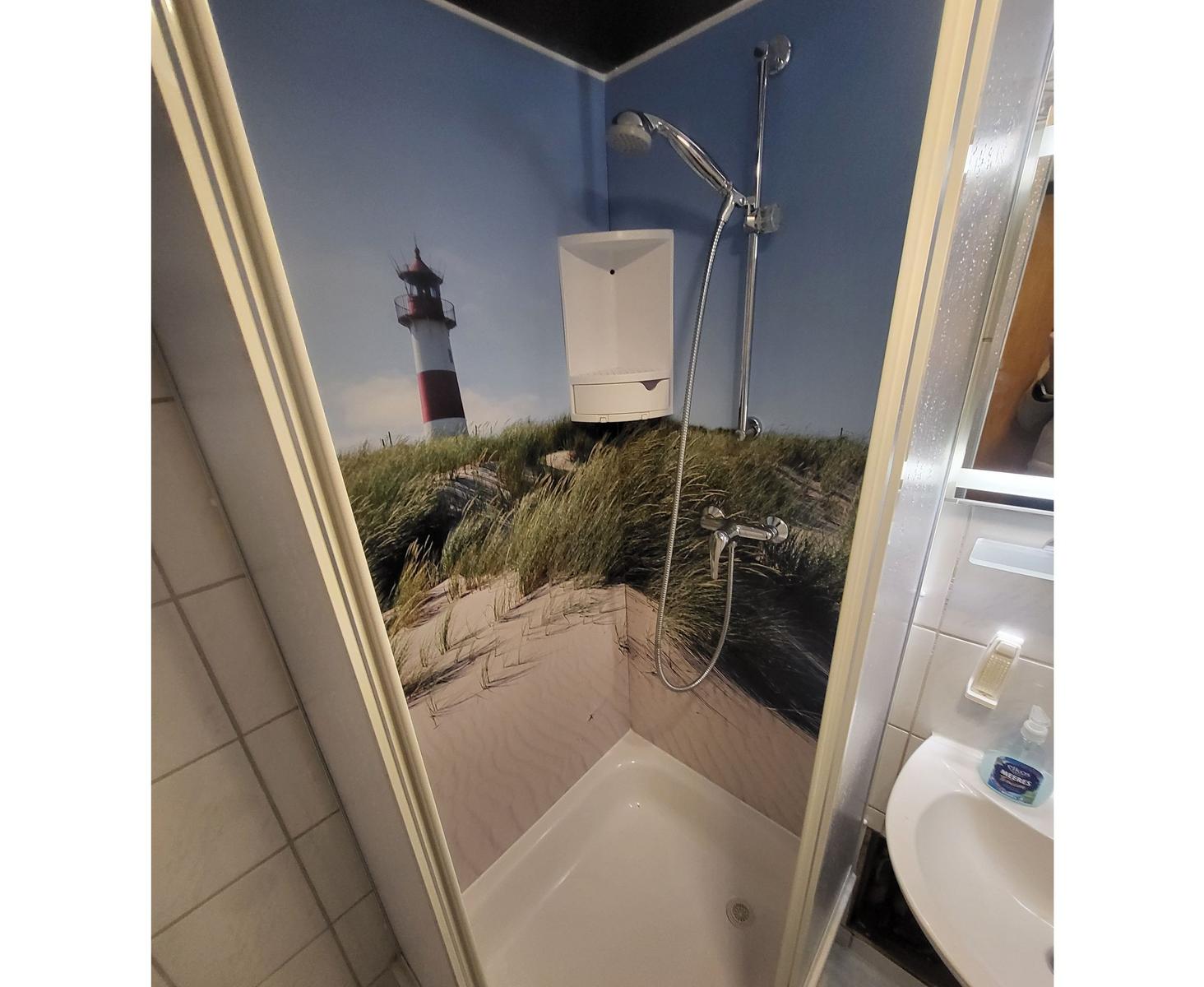 Duschbereich mit Leuchtturm-Motiv an den Wänden und integriertem Duschsystem.
