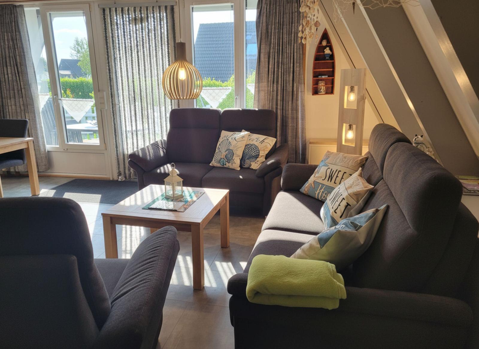 Wohnzimmer mit Sofa, Sitzgelegenheiten und Blick auf Balkon.