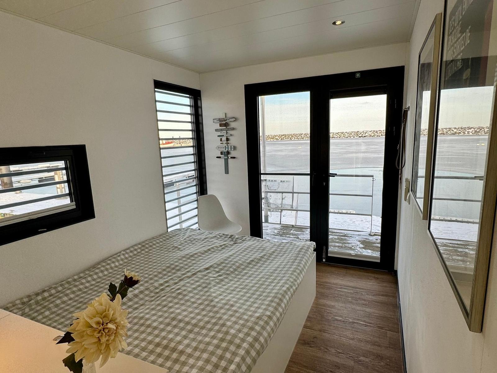 Schlafzimmer mit Bett, Fenster und Balkontür zum Hafen.