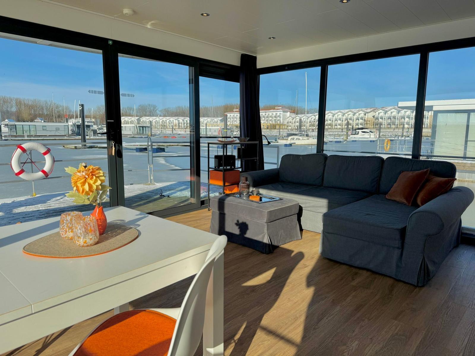 Wohnbereich mit Sofa, Tisch und Blick auf Hafen