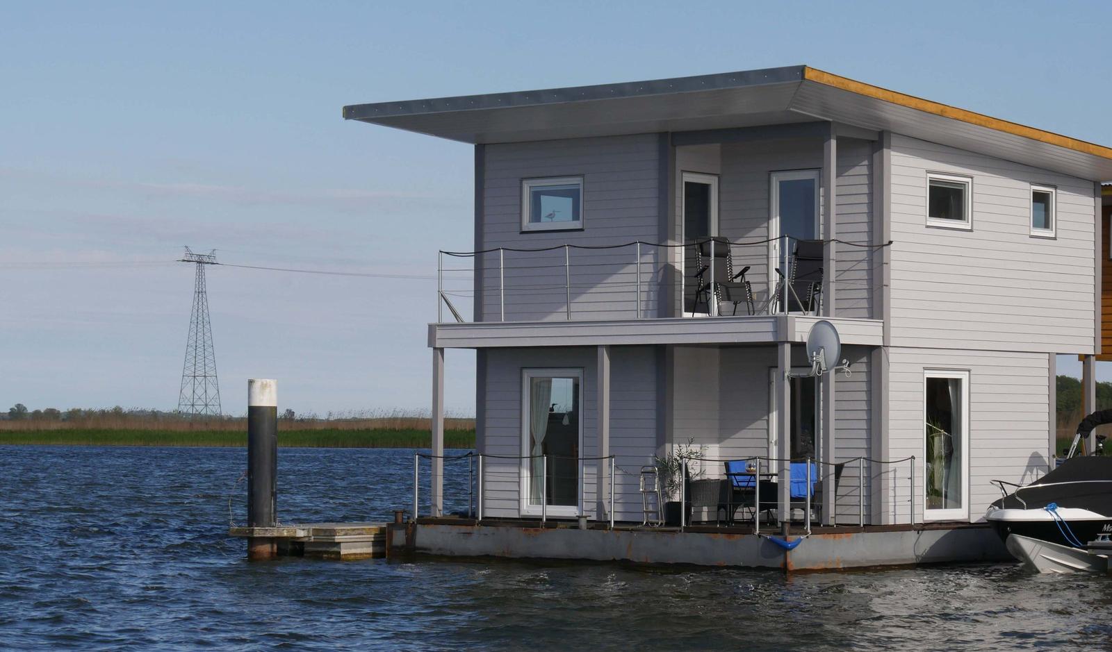 Moderne zweistöckige Bootsvermietung mit Balkon und Terrasse direkt am Wasser.