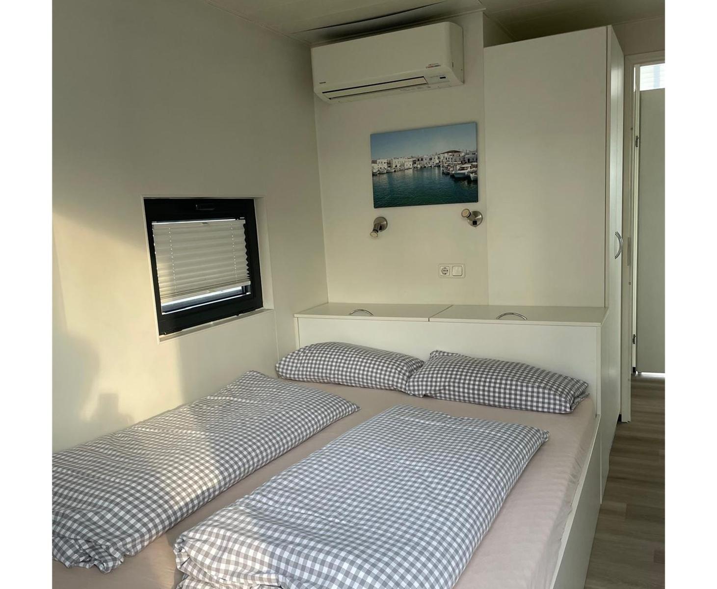 Schlafzimmer mit Doppelbett, Fenster und Klimaanlage.