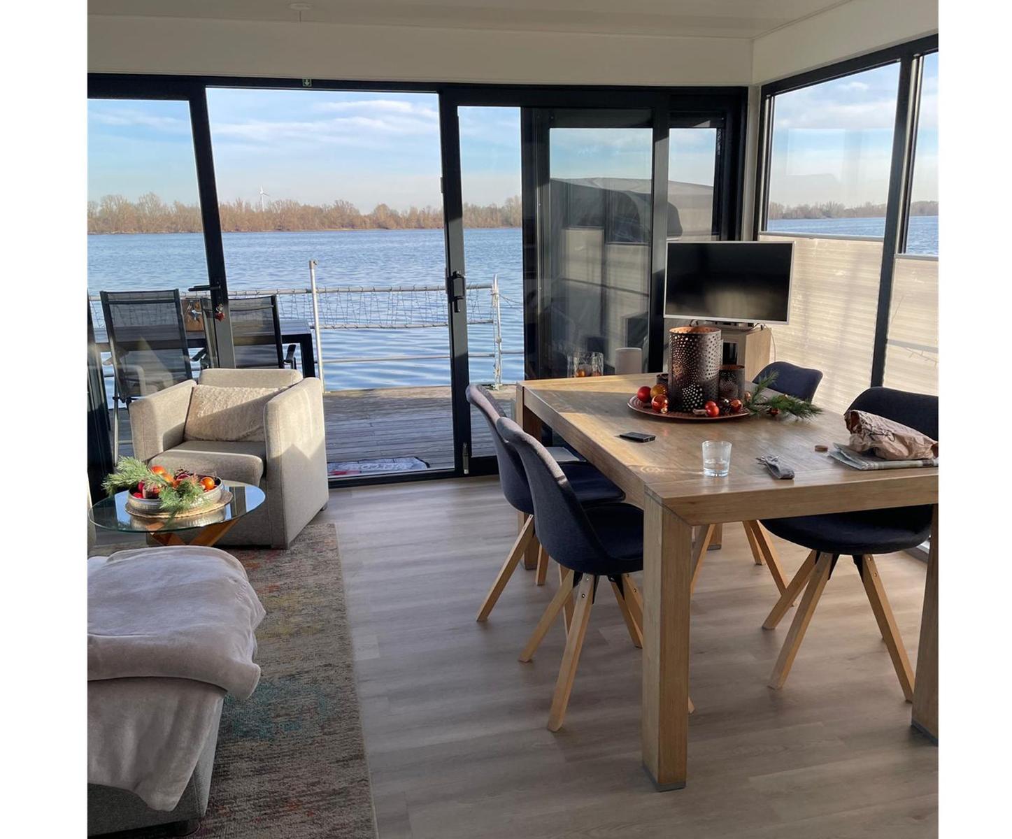 Ein Esszimmer mit Tisch und Stühlen, Fernseher und Blick auf einen See.