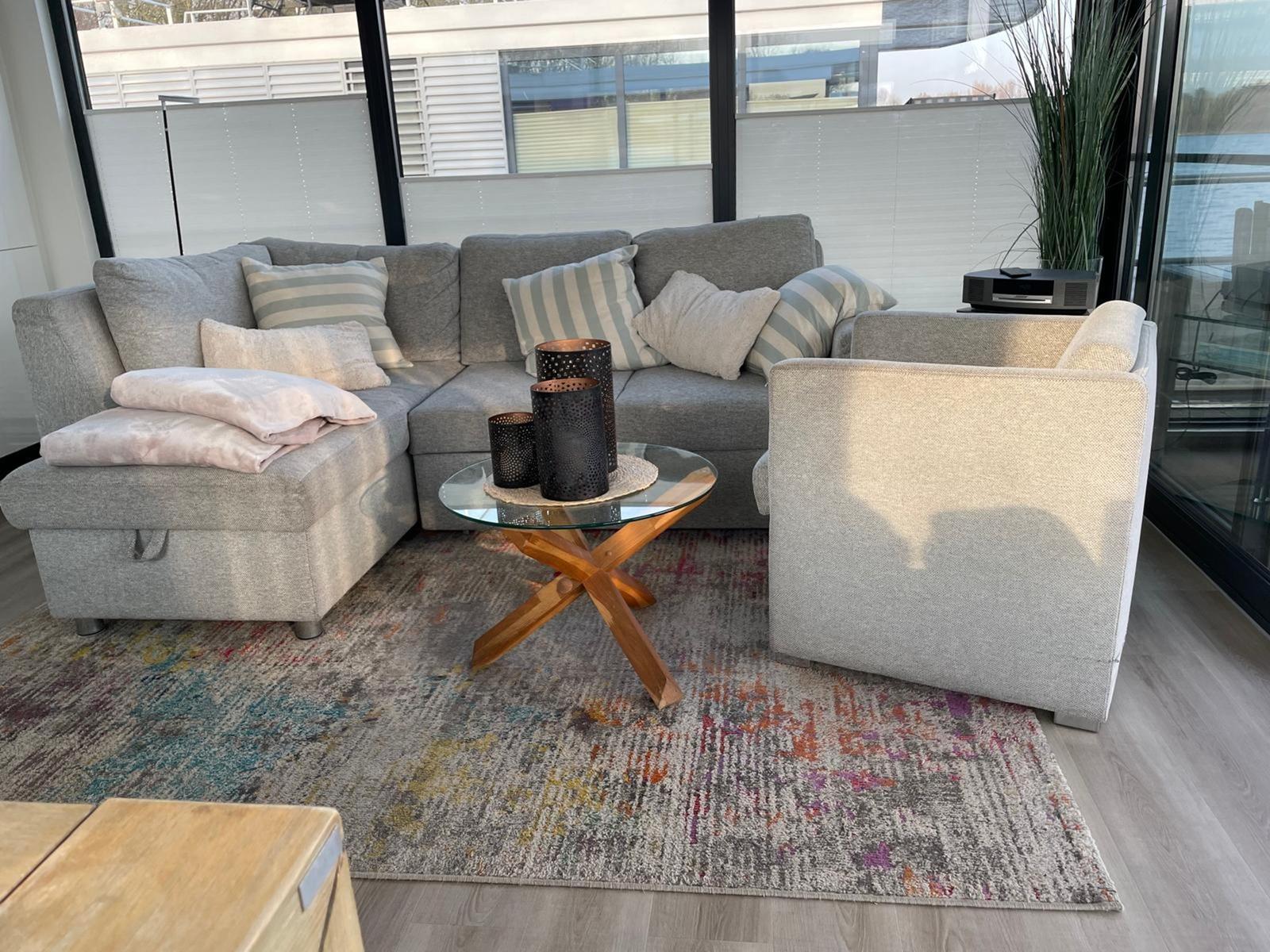Ein Wohnbereich mit grauem Sofa, Beistelltisch und Teppich.