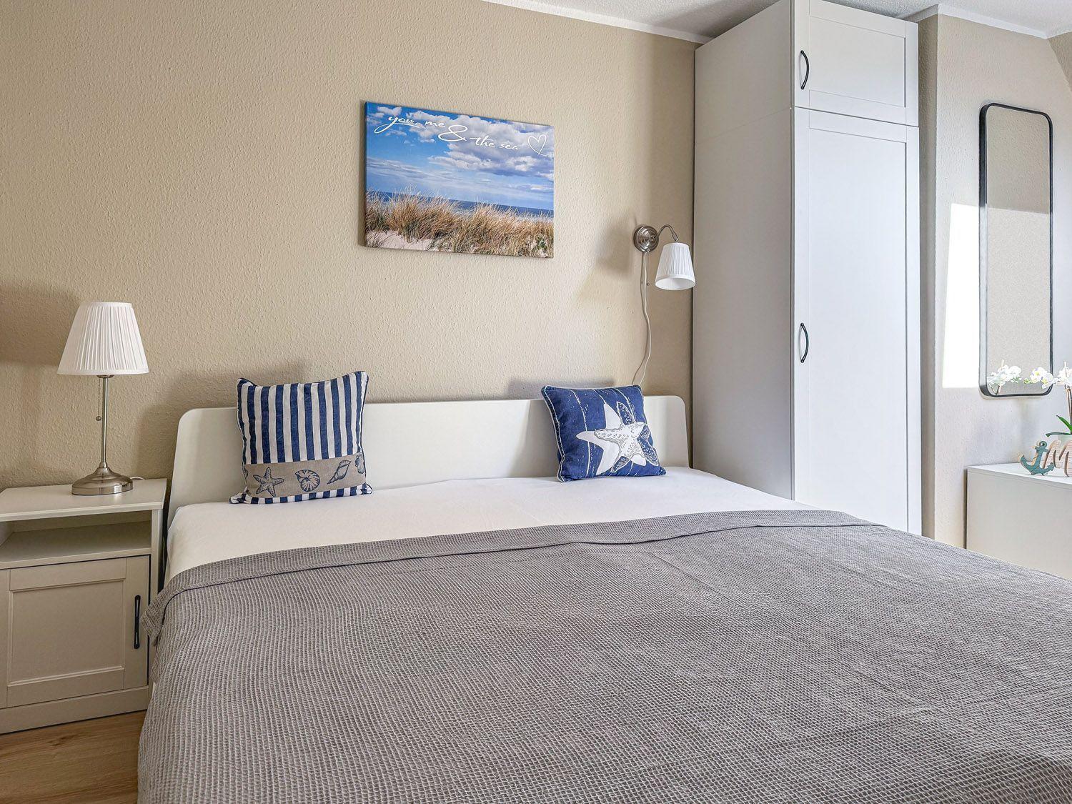 Schlafzimmer mit Bett, Nachttisch, Kleiderschrank und Wandbild.