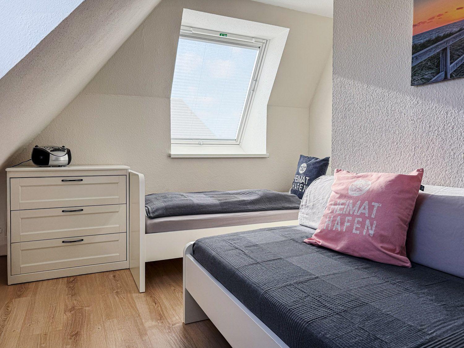 Zimmer mit Dachschrägen, Doppelbett, Schreibtisch und Dachfenster.