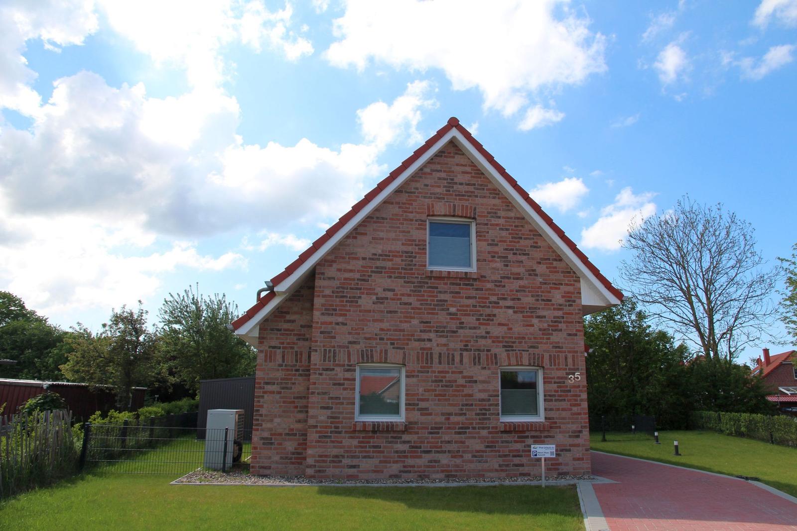 Ein zweistöckiges Haus aus roten Ziegeln mit drei Fenstern und einem roten Dach.