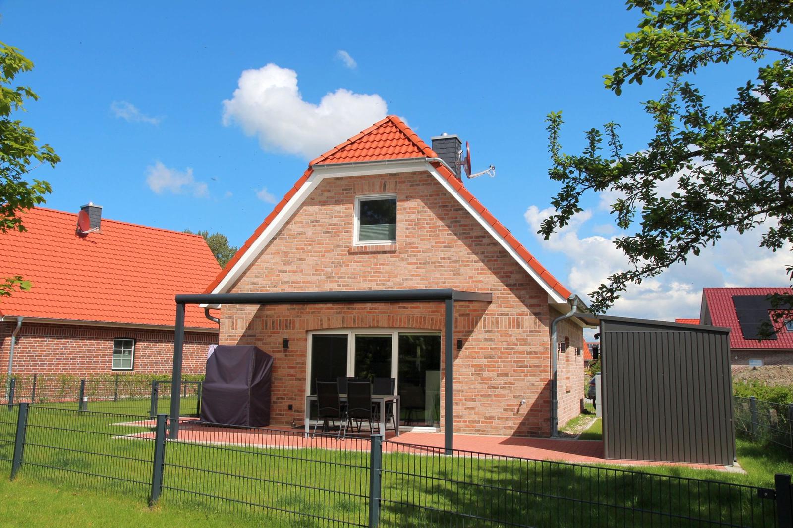 Ein Haus mit rotem Dach und Terrasse mit Garten.