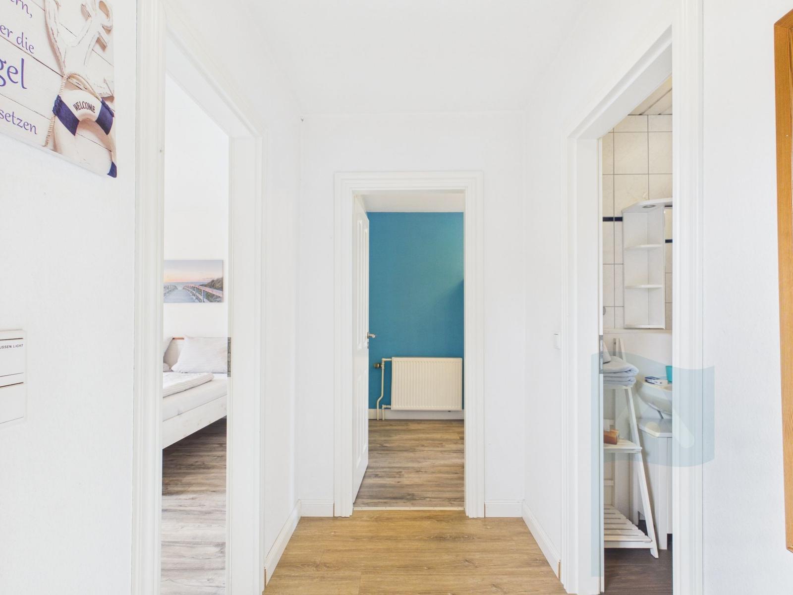 Flur mit Blick in Schlafzimmer, Bad und Raum mit blauer Wand.