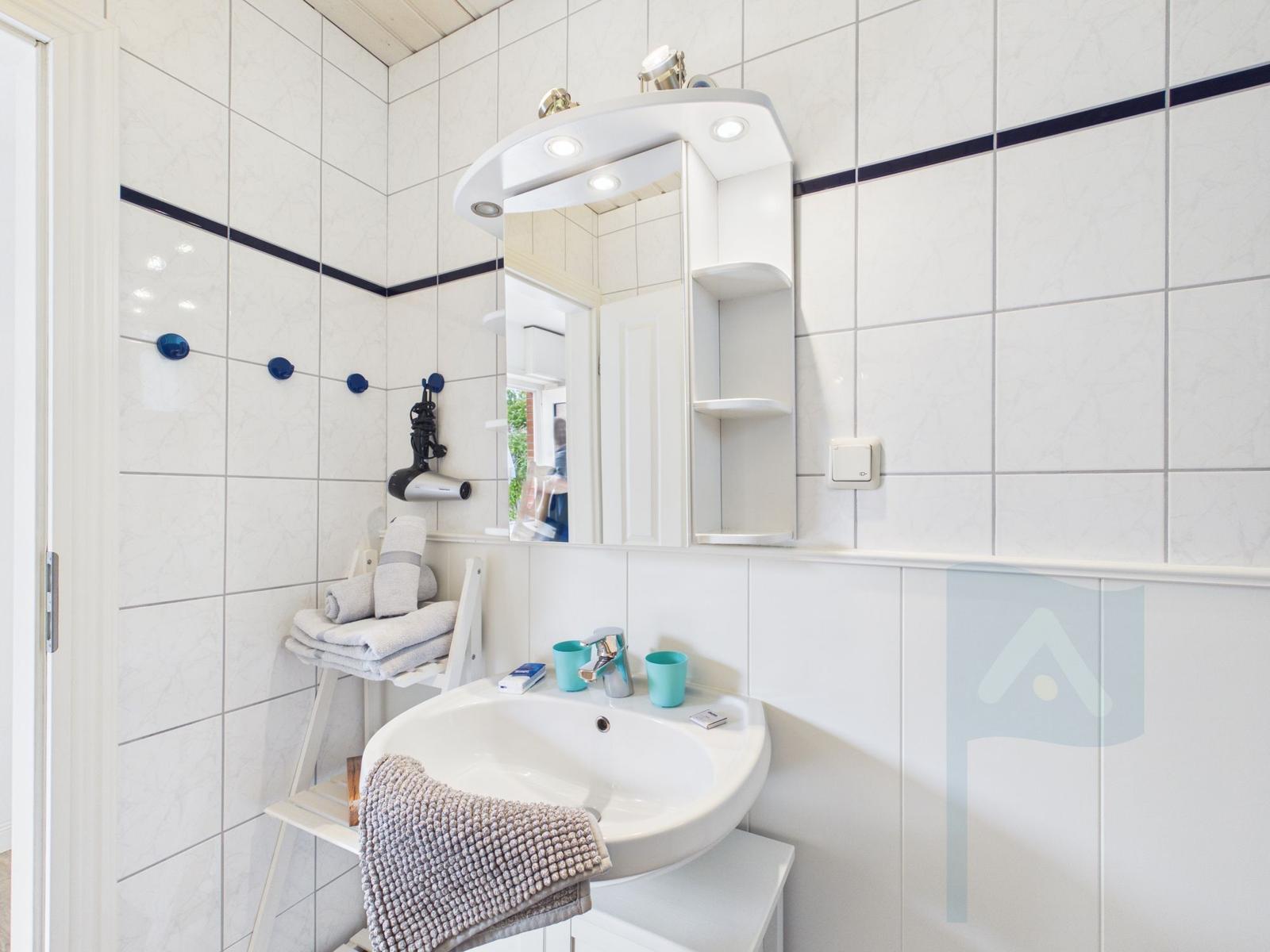 Badezimmer mit Waschbecken, Spiegel und Handtuchständer