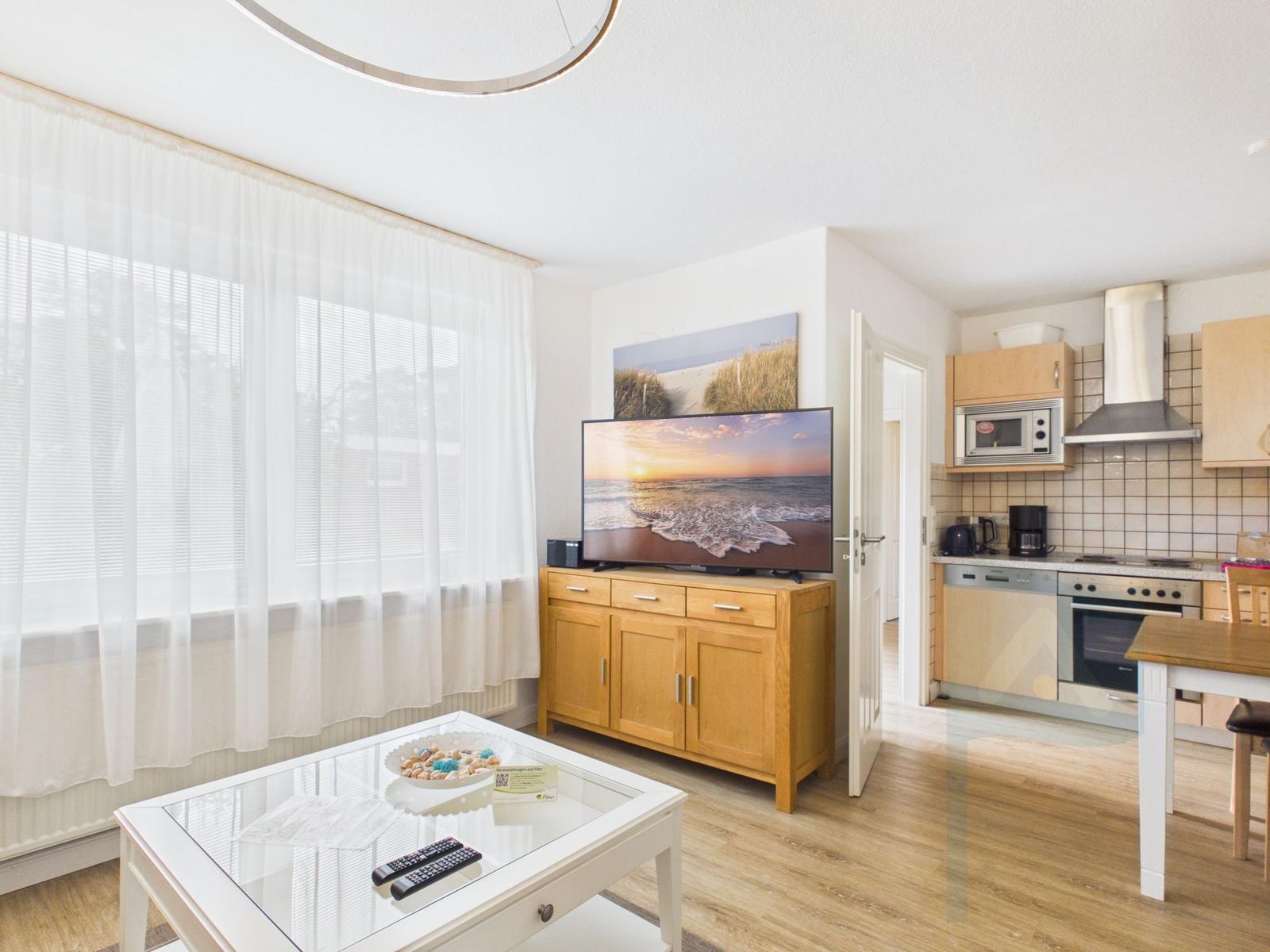 Wohn- und Küchenbereich mit TV, Holzmöbeln und Fenster