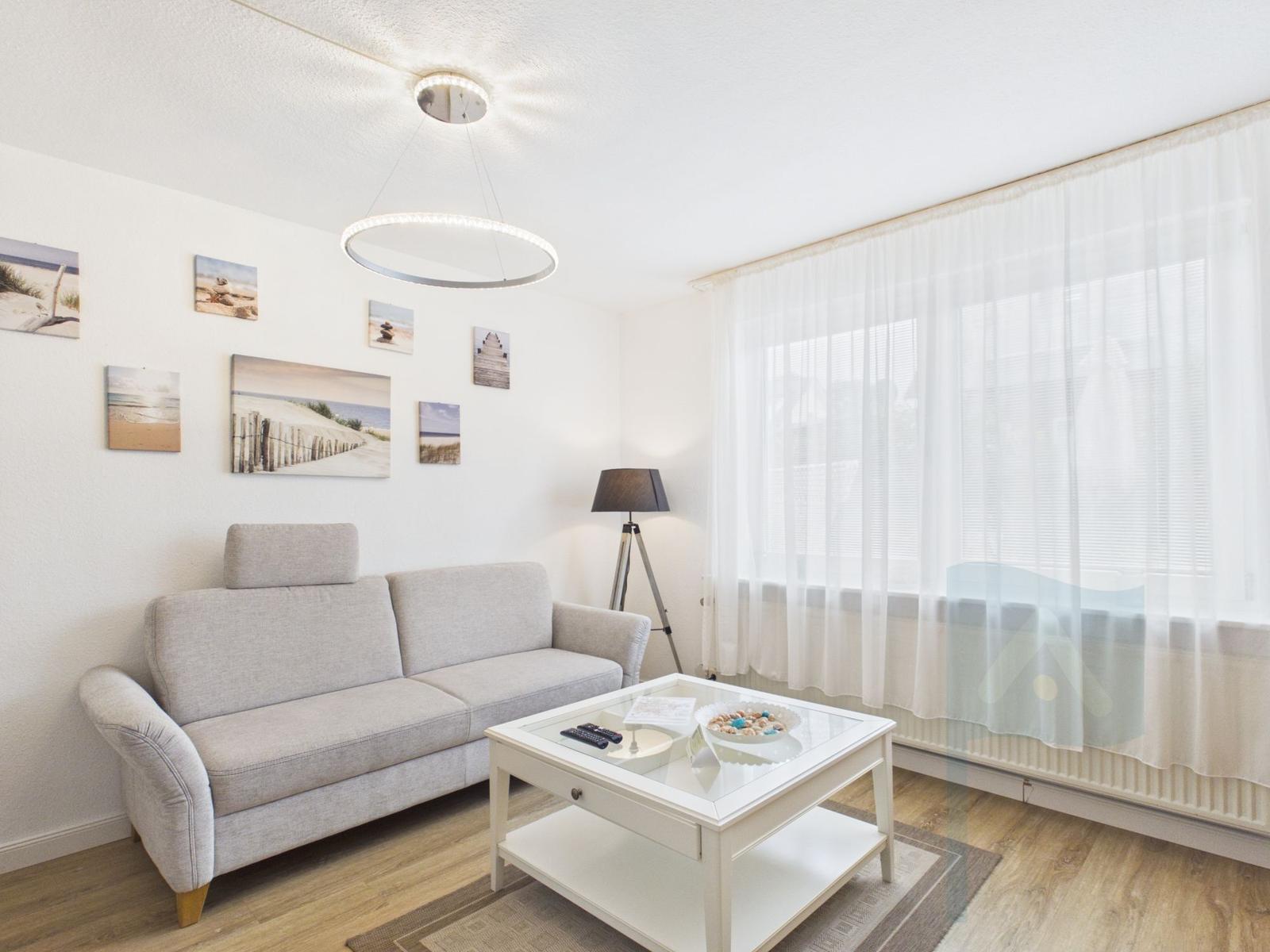 Wohnzimmer mit Sofa, Couchtisch und Wandbildern an der Wand.
