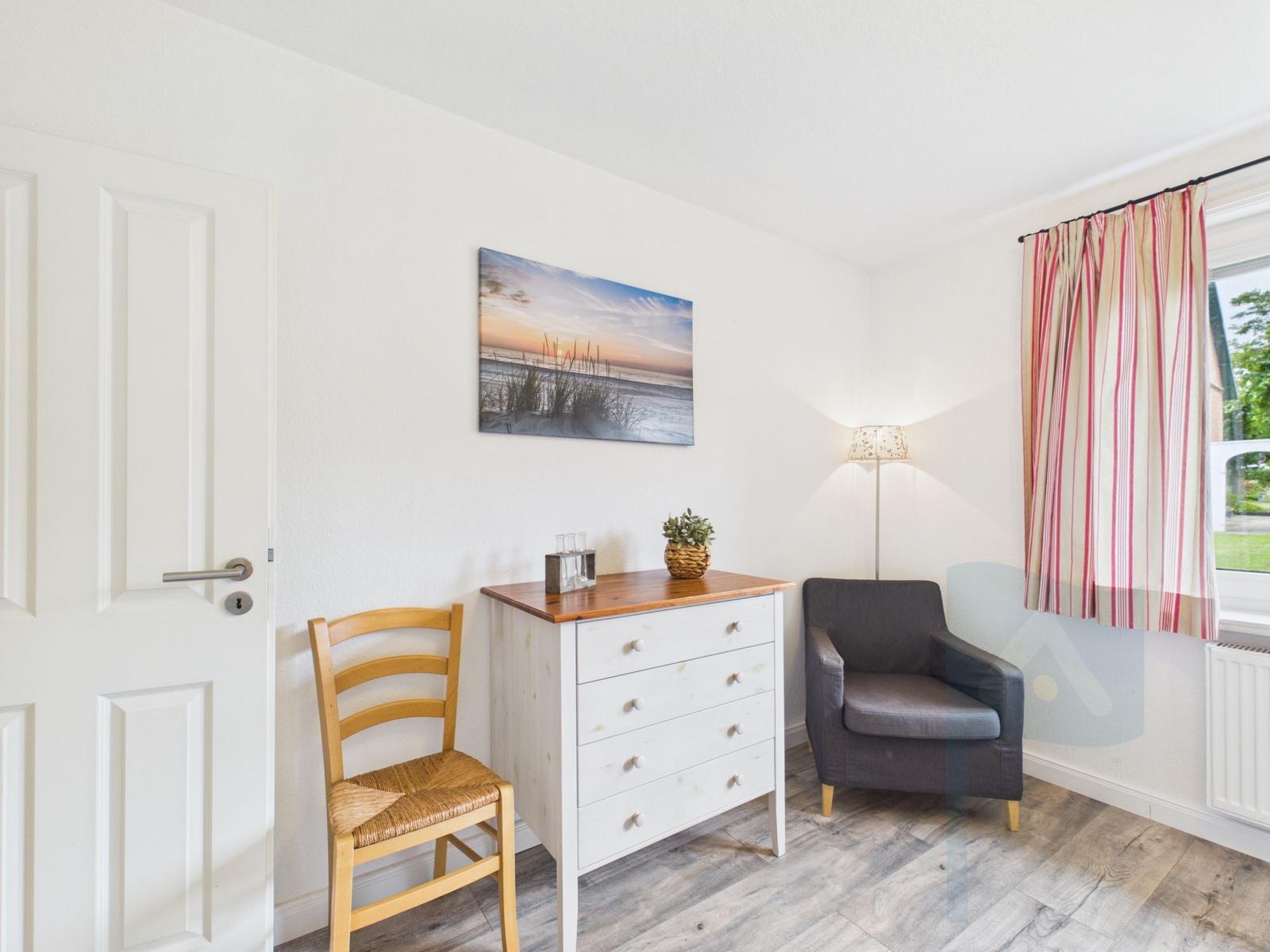 Ein Raum mit Stuhl, Schrank, Sessel und Bild an der Wand.
