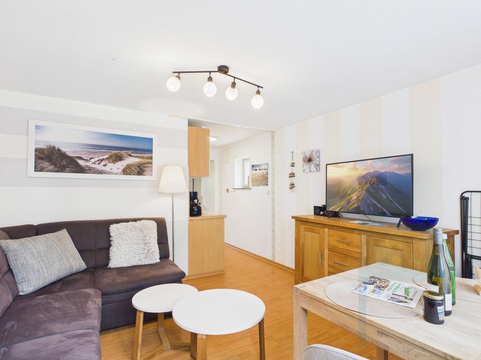 Wohnzimmer mit Sofa, Fernseher und Tisch. Wandbild und Holzmöbel sichtbar.
