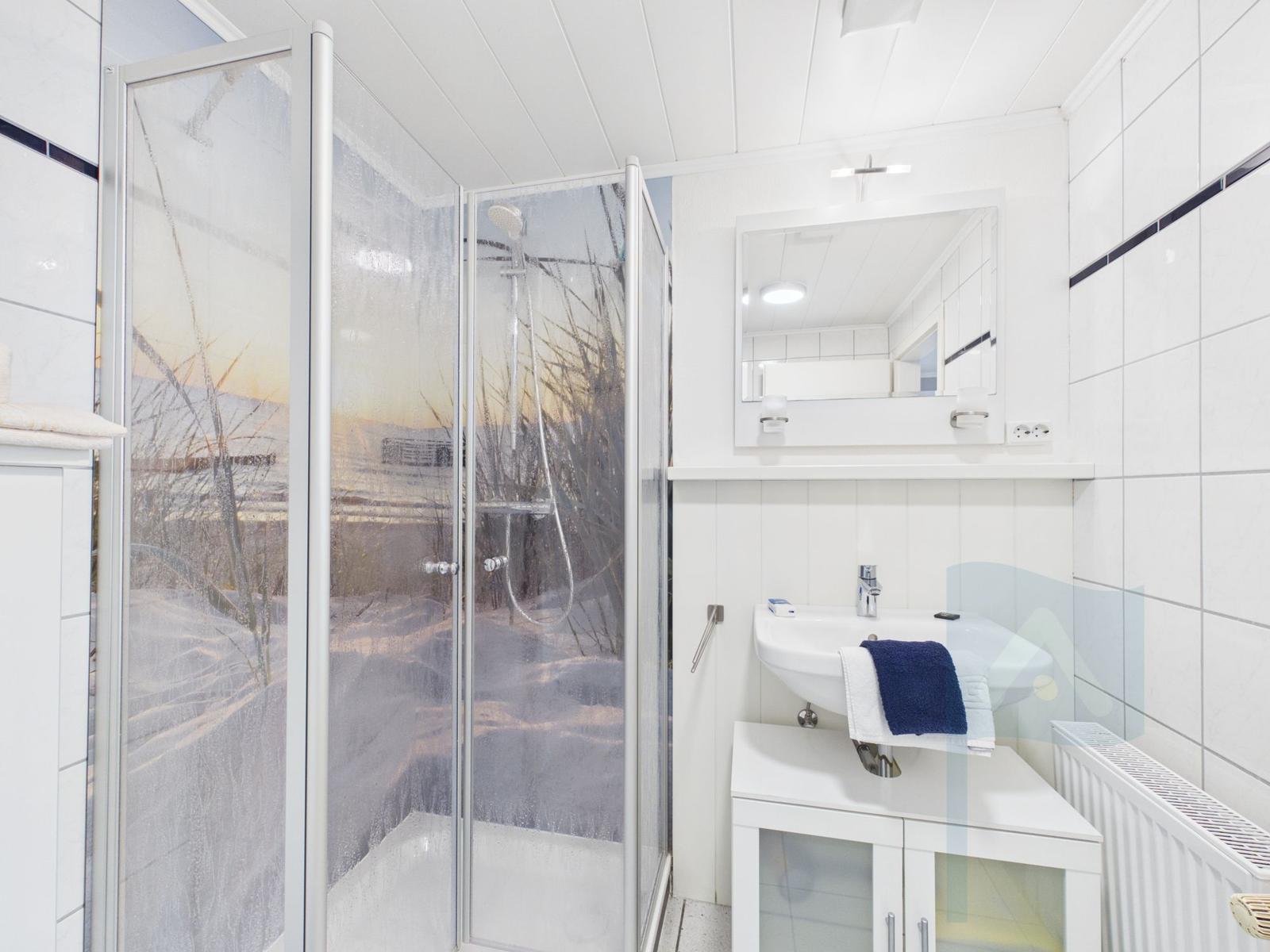 Badezimmer mit Dusche, Waschbecken und Spiegel