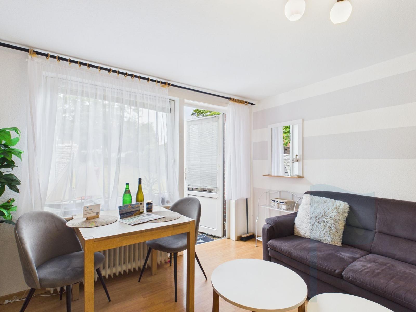 Wohnzimmer mit Sofa, Esstisch und Fenster. Wand mit Streifenmuster.