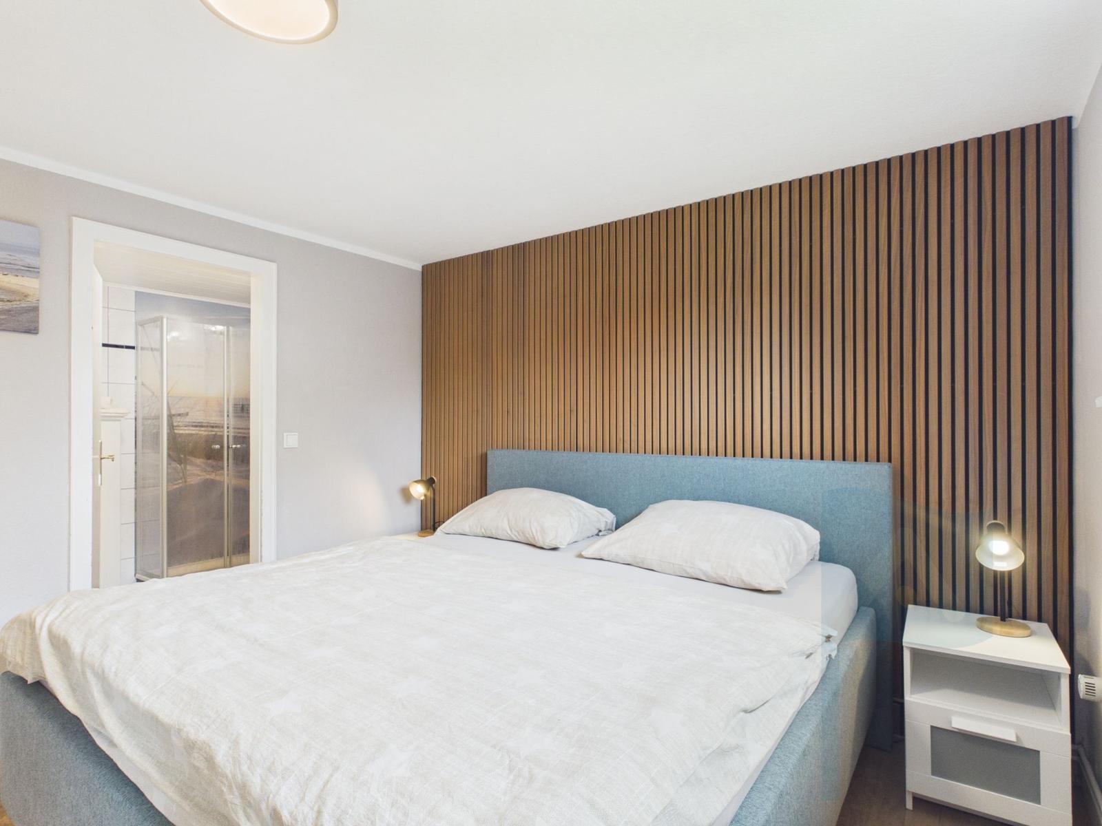 Schlafzimmer mit Doppelbett, Holzwand und Nachttisch