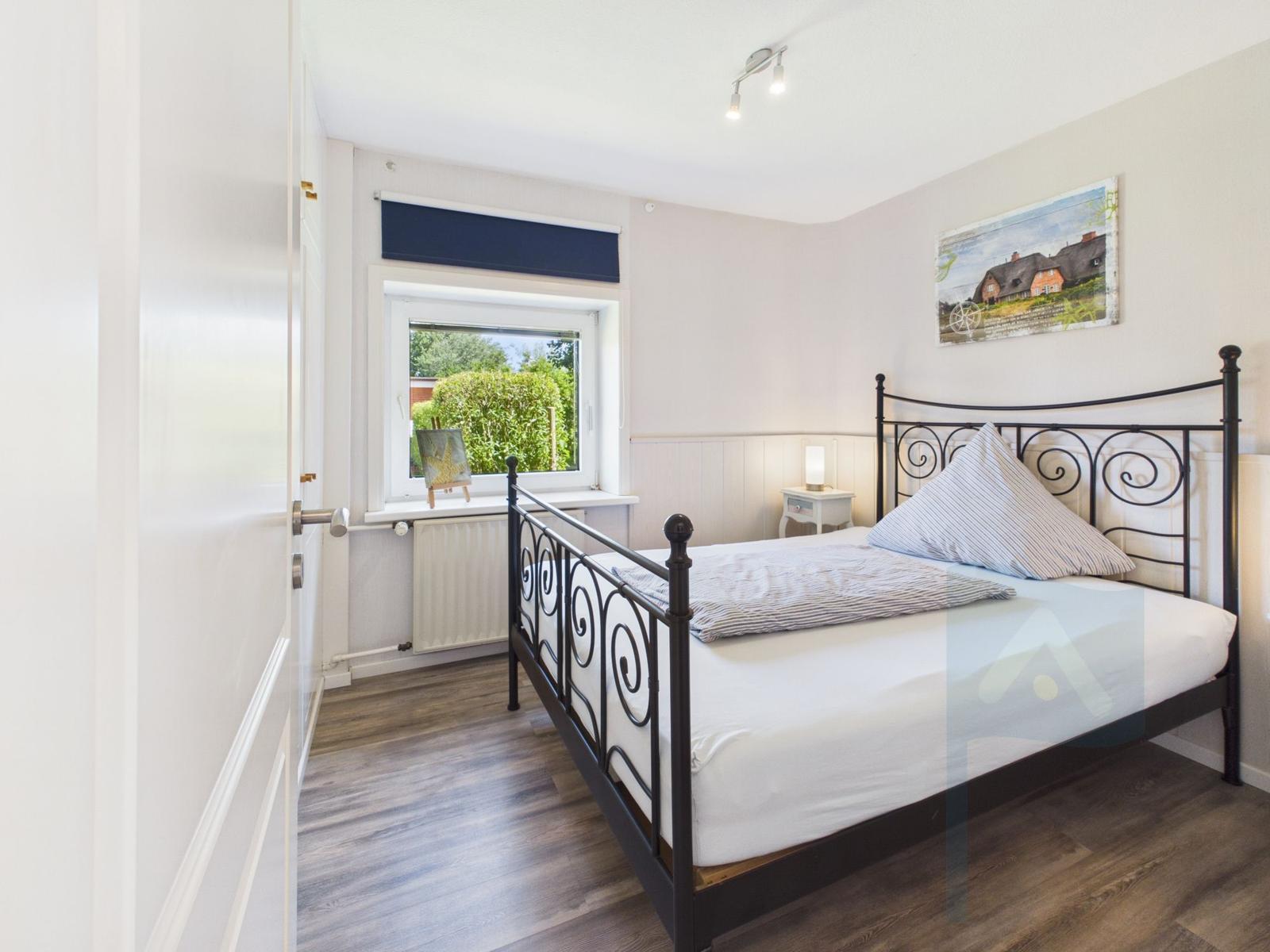 Bedroom with bed, window, and wall picture.