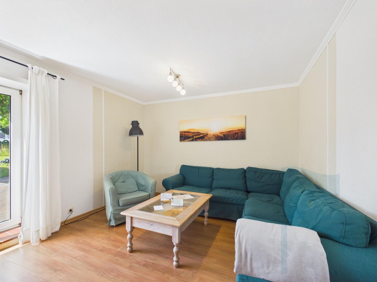 Living room with sofa, armchair, and table. A picture hangs on the wall.
