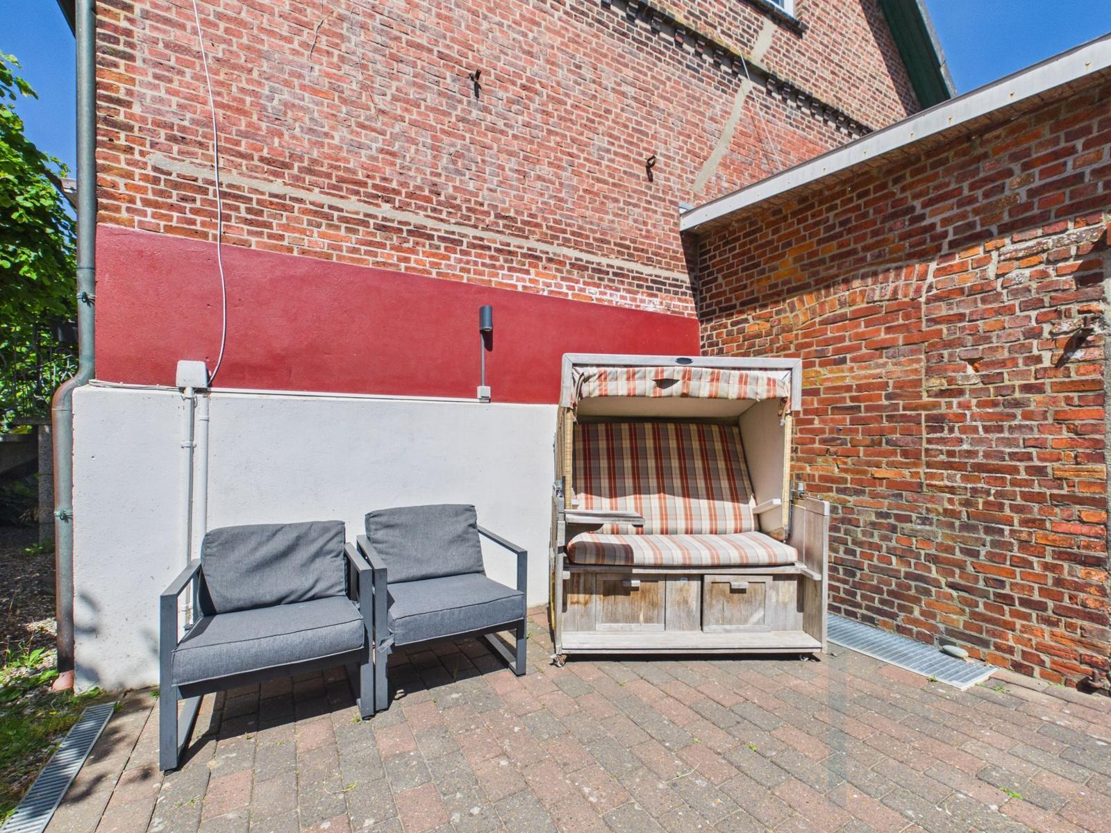 Outdoor area with two seating options and a beach chair against brick walls.