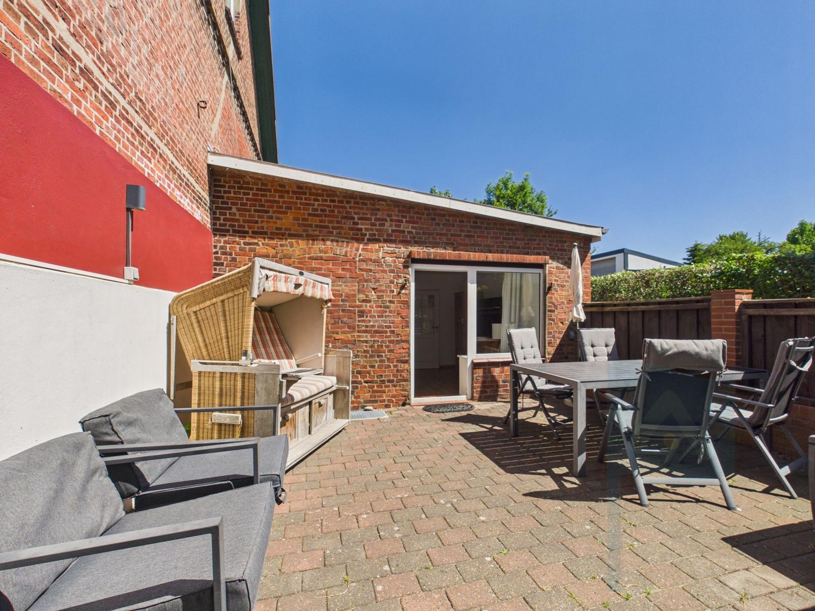 Terrace with seating, lounge, and garden table in front of brick house