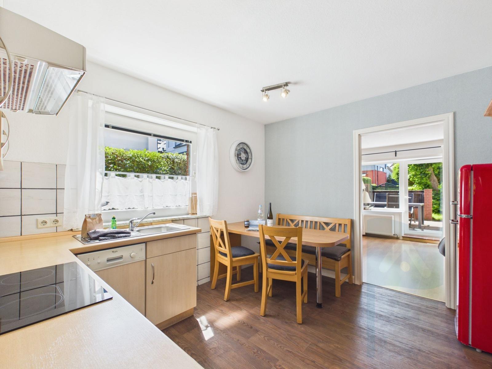 Kitchen with dining table, red fridge, and view to terrace.