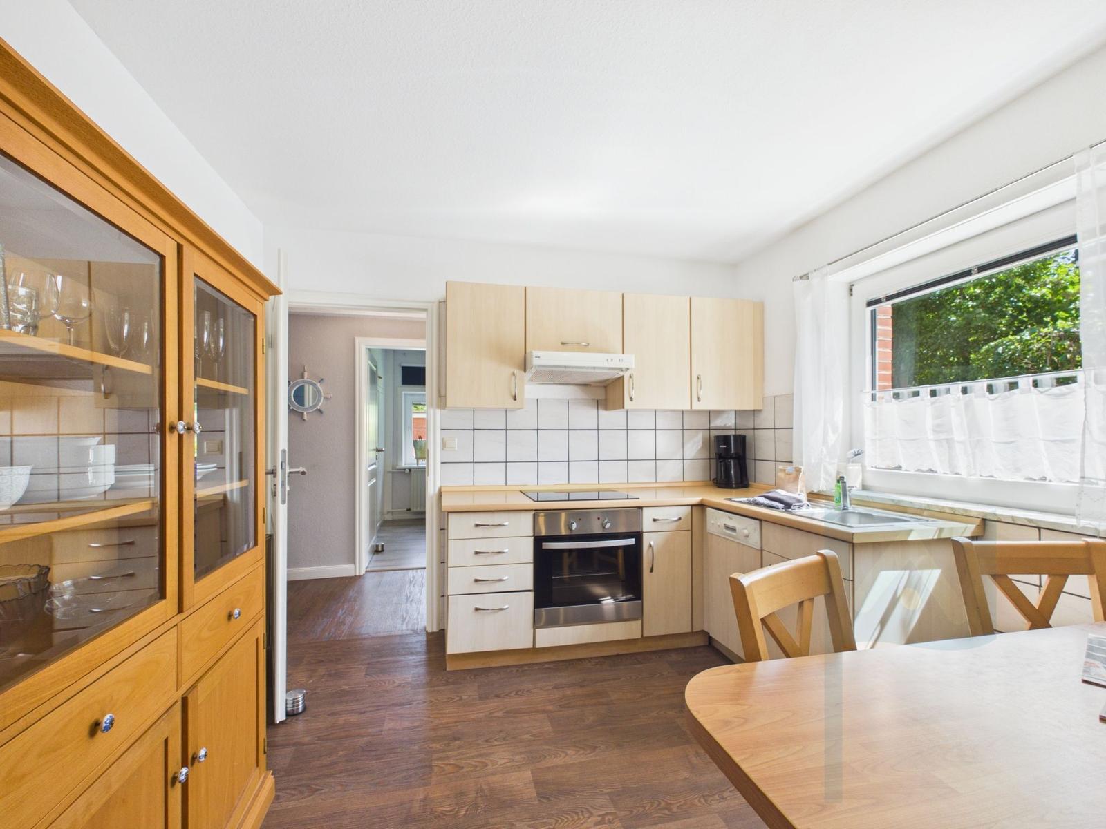 Kitchen with wooden furniture, stove, and window with garden view