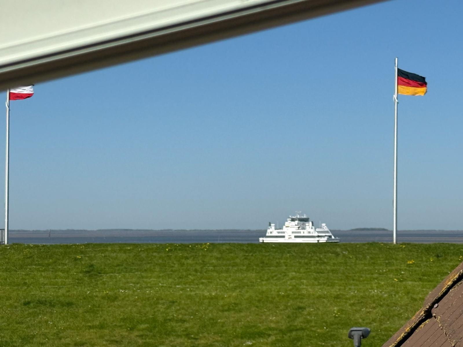 Ferries fahren unter deutschen und polnischen Flaggen im Hafen vorbei.
