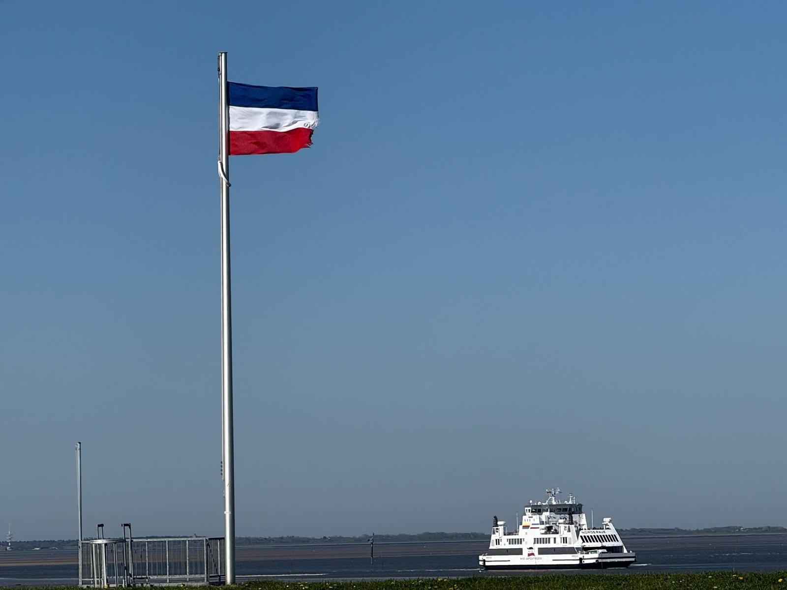 Fahrrinne mit Flagge und Fähre im Hafen.