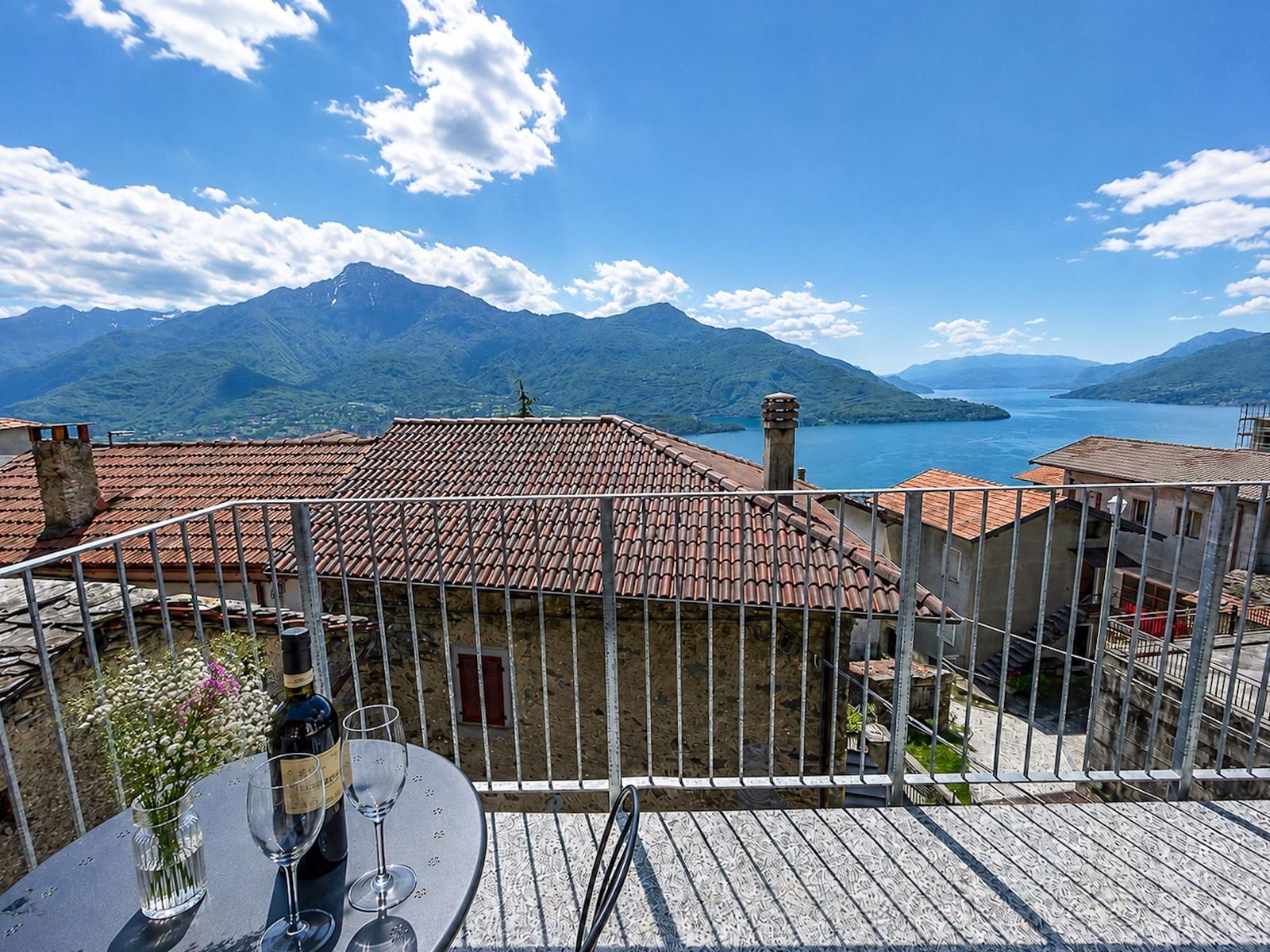 Terrasse mit Tisch, Wein und Blick auf See und Berge.