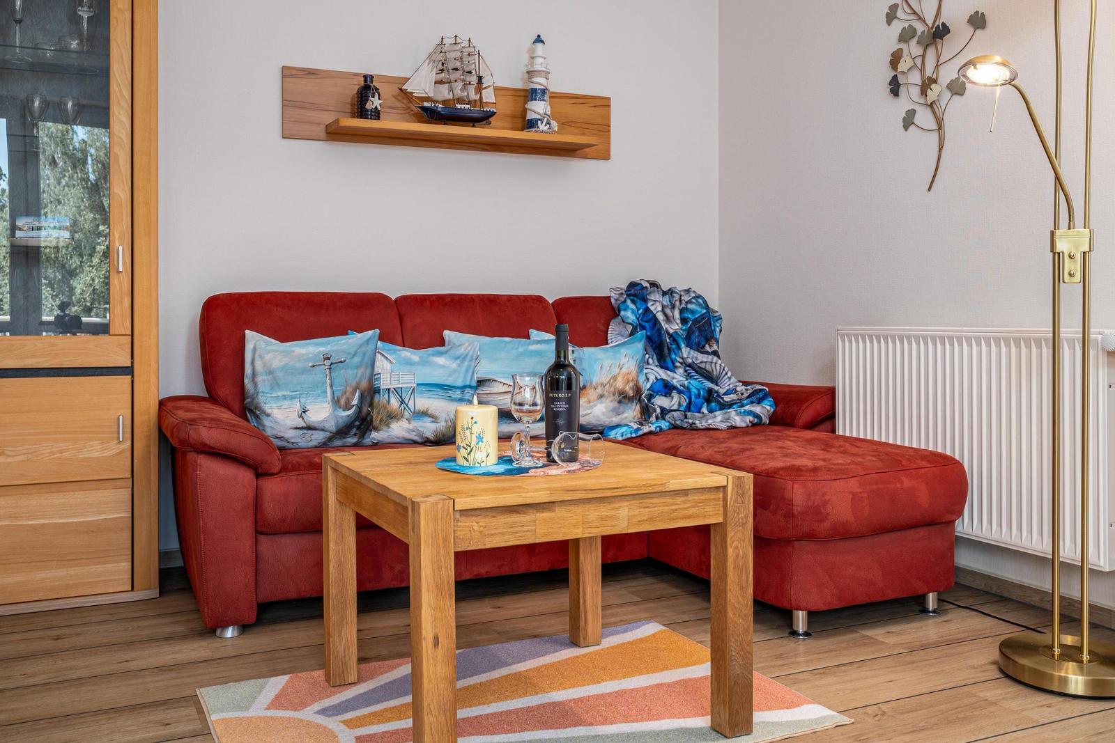 Rotes Sofa mit Kissen, Holztisch und Stehlampe im Wohnzimmer.