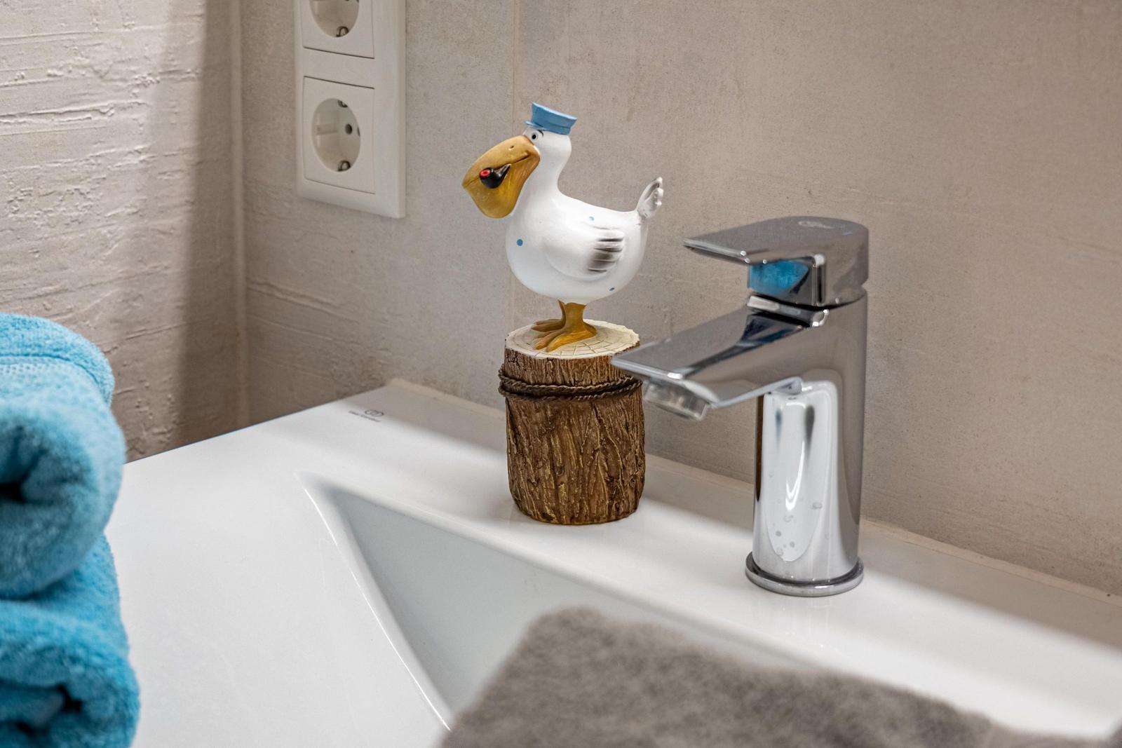 Waschbecken mit Hahn und Vogel-Dekoration auf Holzstumpf