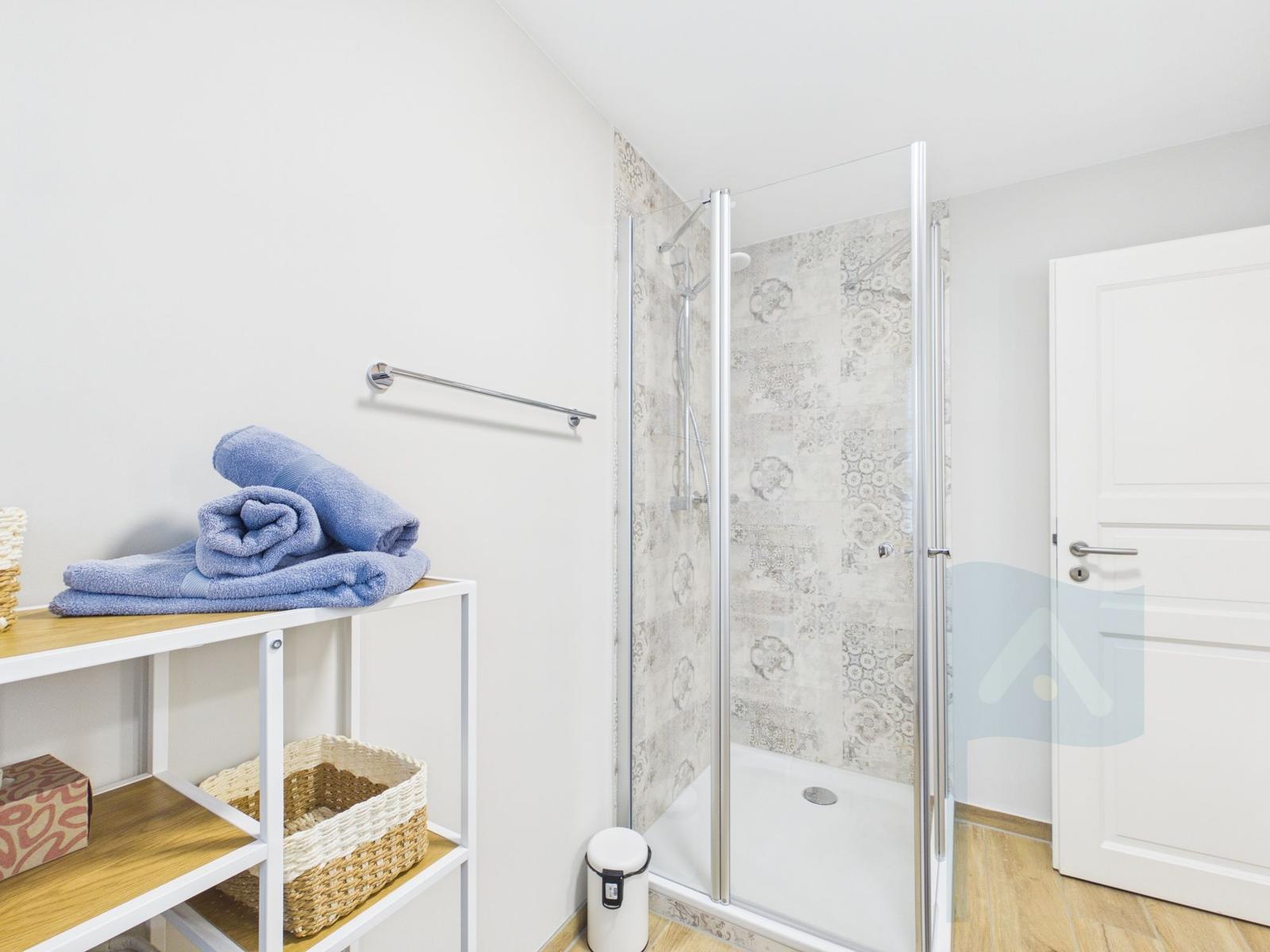 Bad mit Dusche, Handtuchregal und Holzboden.