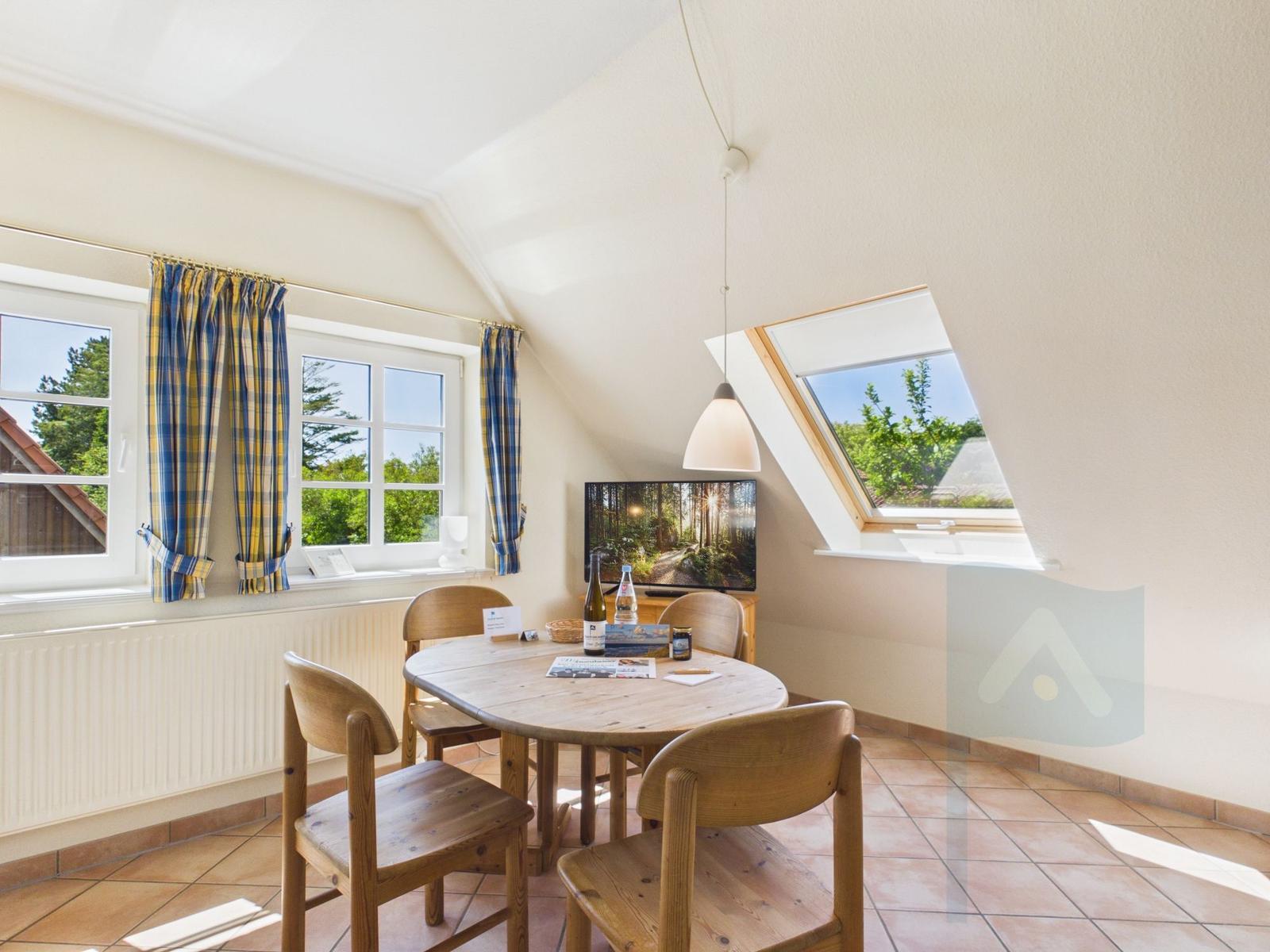 Esszimmer mit Holztisch, Stühlen und Fenstern mit Blick auf Grünflächen.