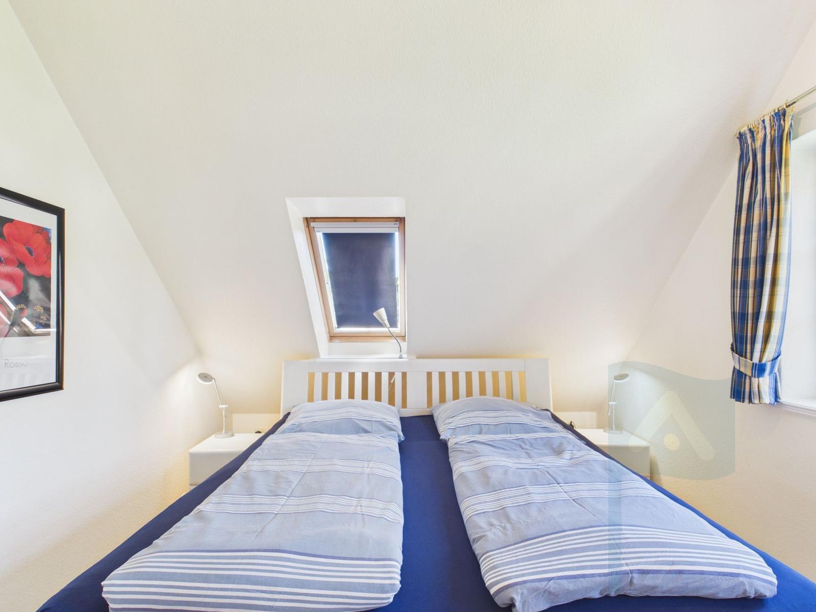 Schlafzimmer mit Doppelbett, Dachfenster und Wandbild.