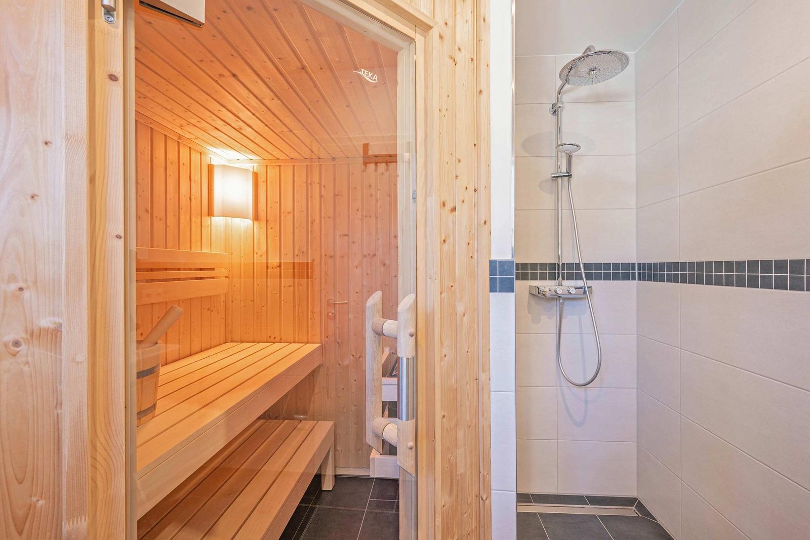 Sauna mit Holzbank und Dusche mit Duschbrause