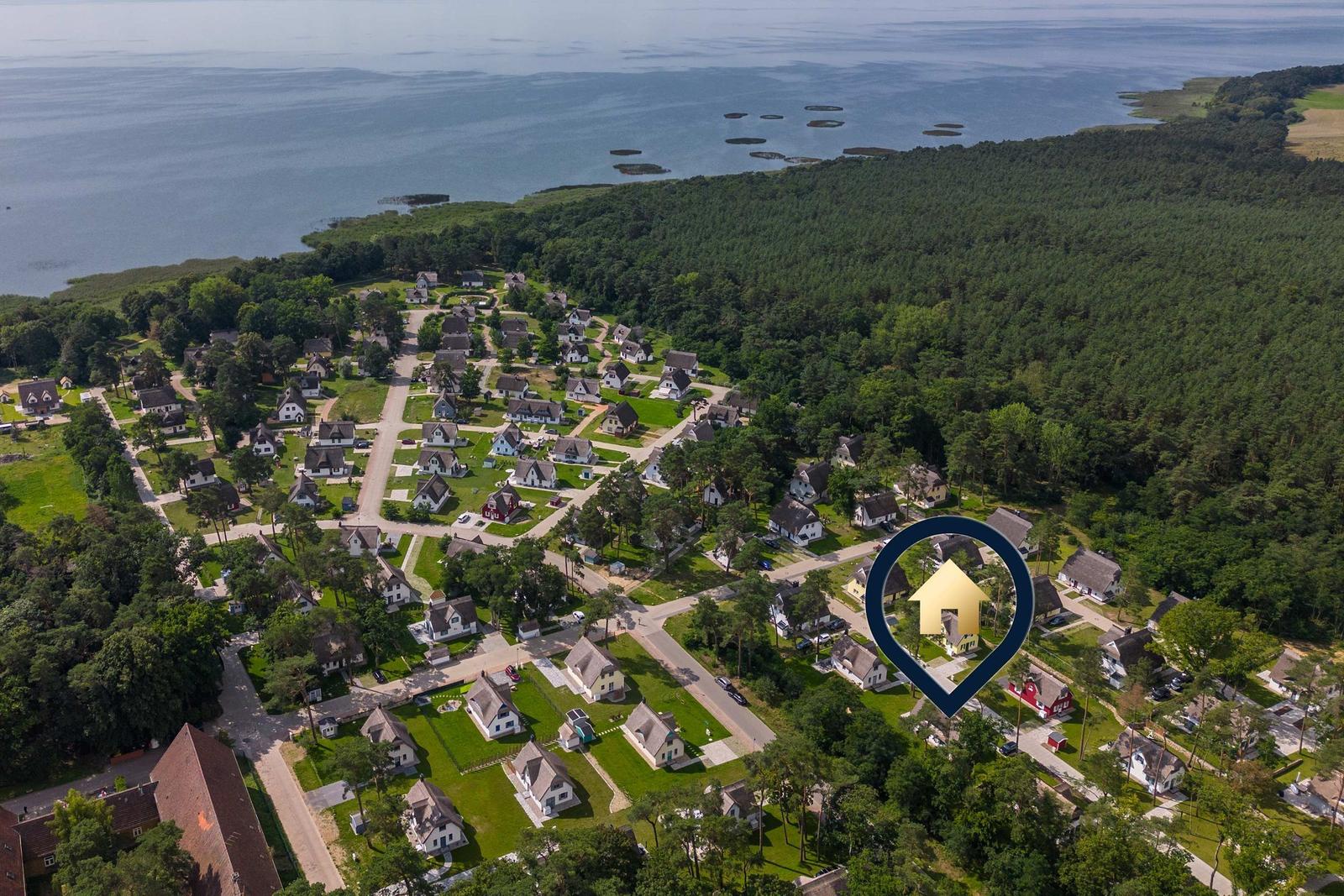 Luftbild eines Ferienorts mit Häusern, Wald und Wasser. Ein Haus ist markiert.