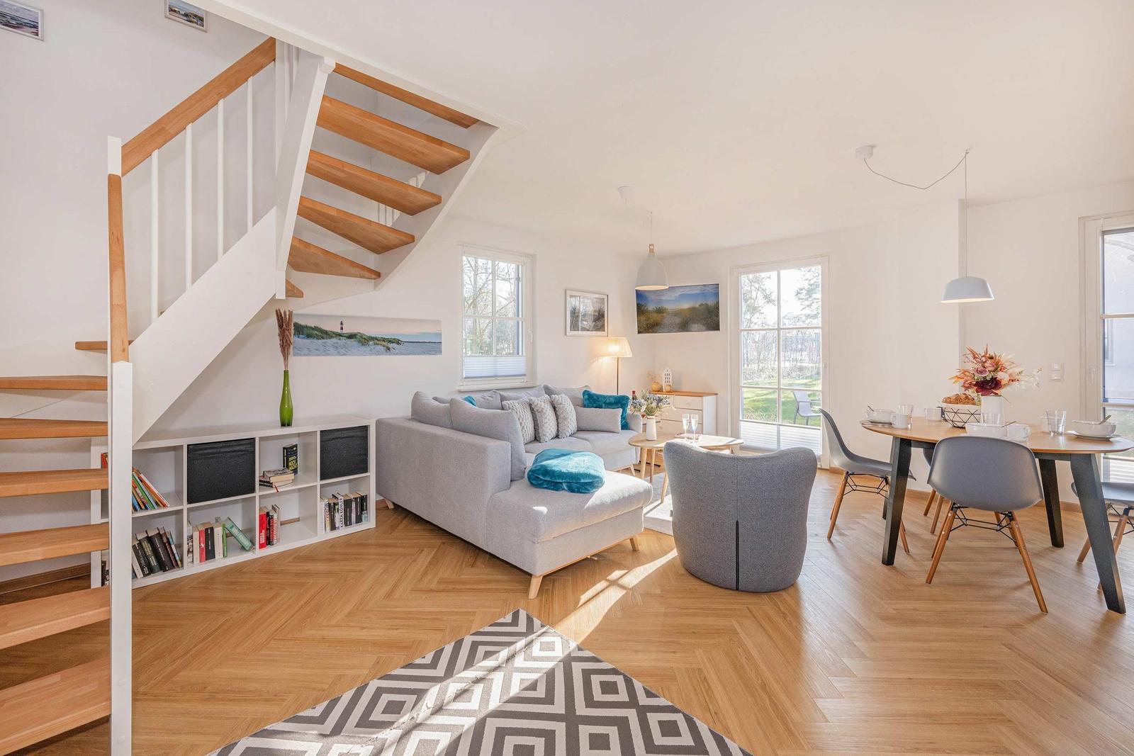 Wohn- und Essbereich mit Holzfußboden, Treppenhaus und moderner Einrichtung.