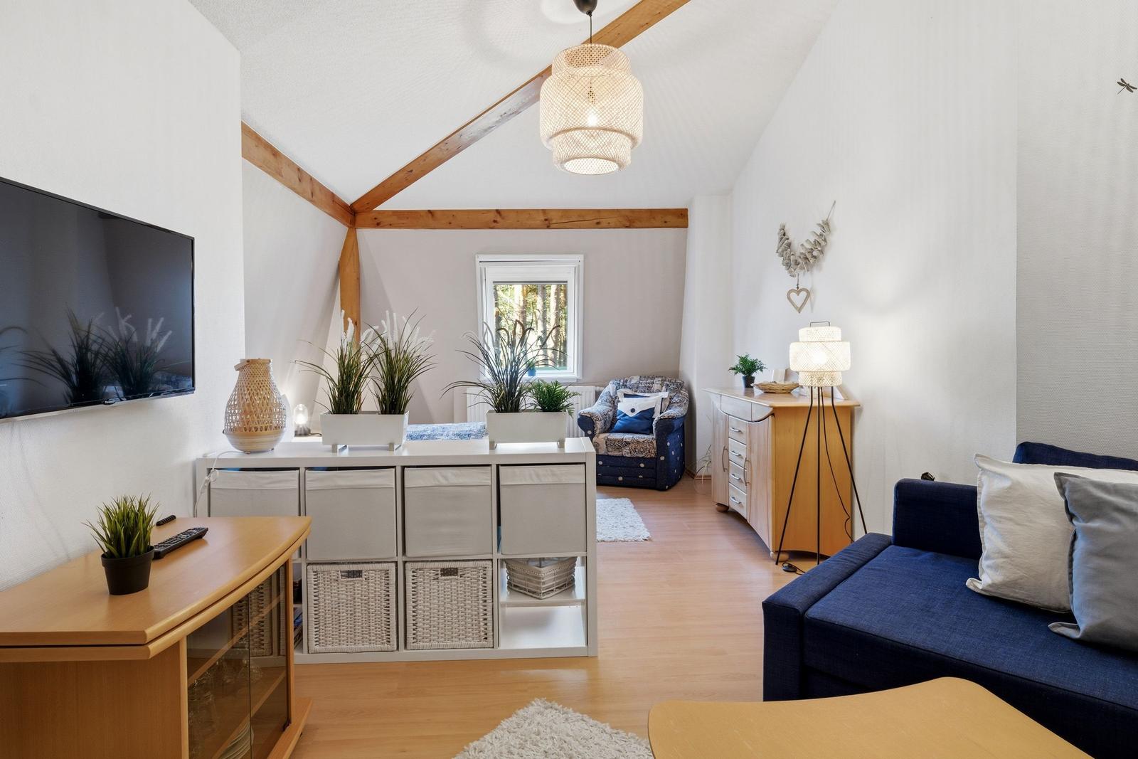 Living room with sofa, TV, and wooden floor. Attic structure with wooden beams.
