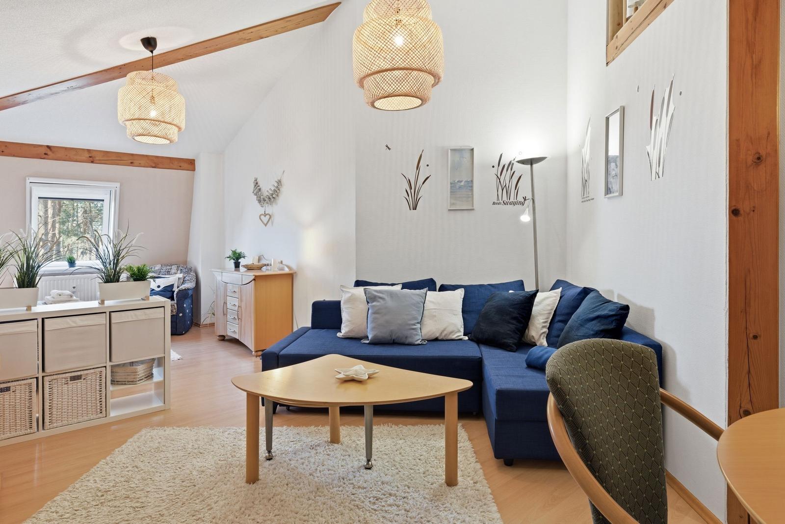 Living room with blue sofa, wooden table, and wall decor.