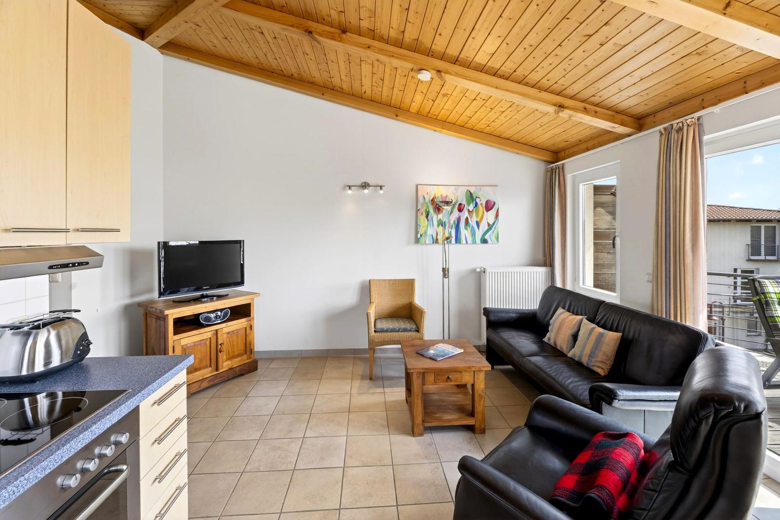 Wohnung mit Küche, Wohnbereich, Sofa, Fernseher und Balkon.