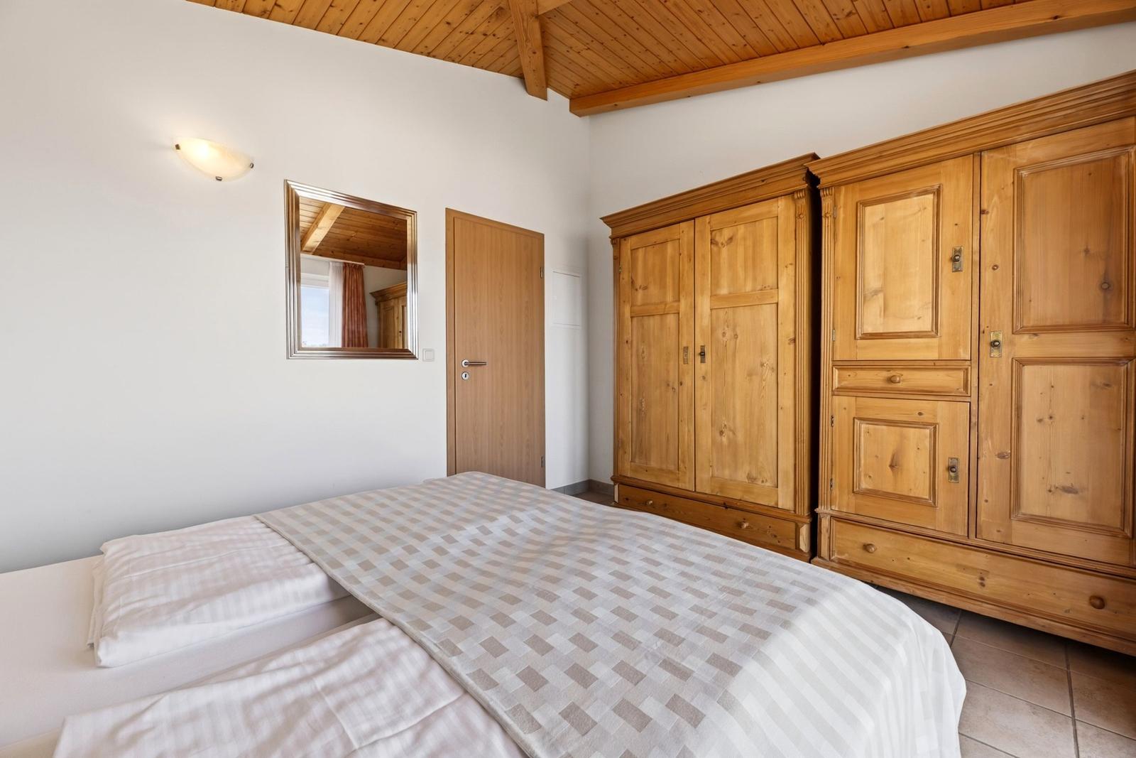 Schlafzimmer mit Holzboden, Bett und zwei großen Holzschranken.
