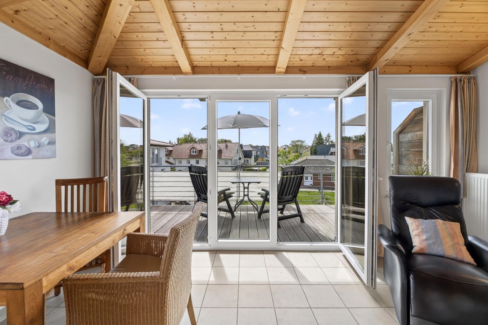 Raum mit Holzdecke, Terrasse mit Tisch und Stühlen, Blick auf Wohnhäuser.