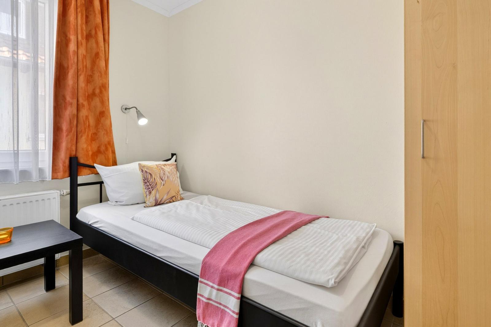 Ein Schlafzimmer mit einem Bett, einem Kleiderschrank und einem Fenster mit Vorhängen.