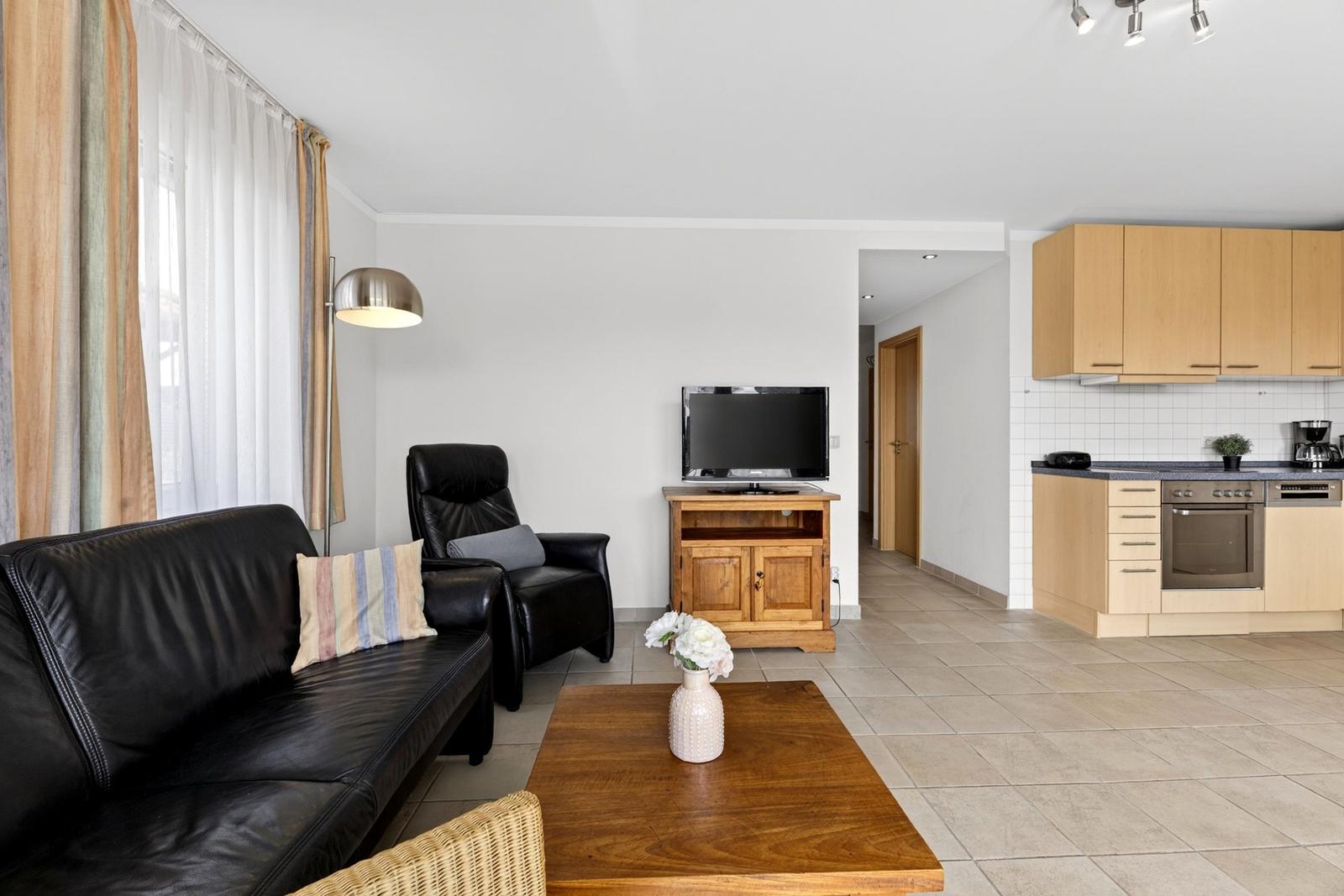 Wohnbereich mit Sofa, Sessel und Küchenbereich mit Holzmöbeln