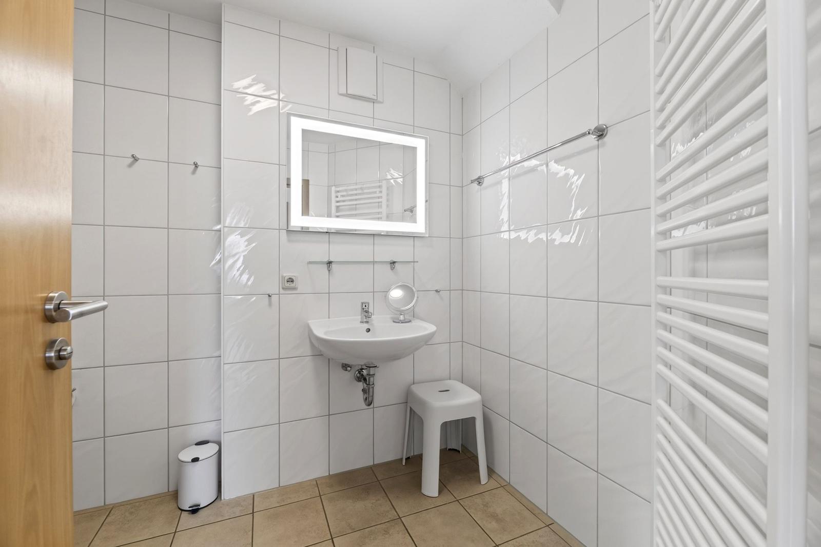 Badezimmer mit Waschbecken, Spiegel und Heizung