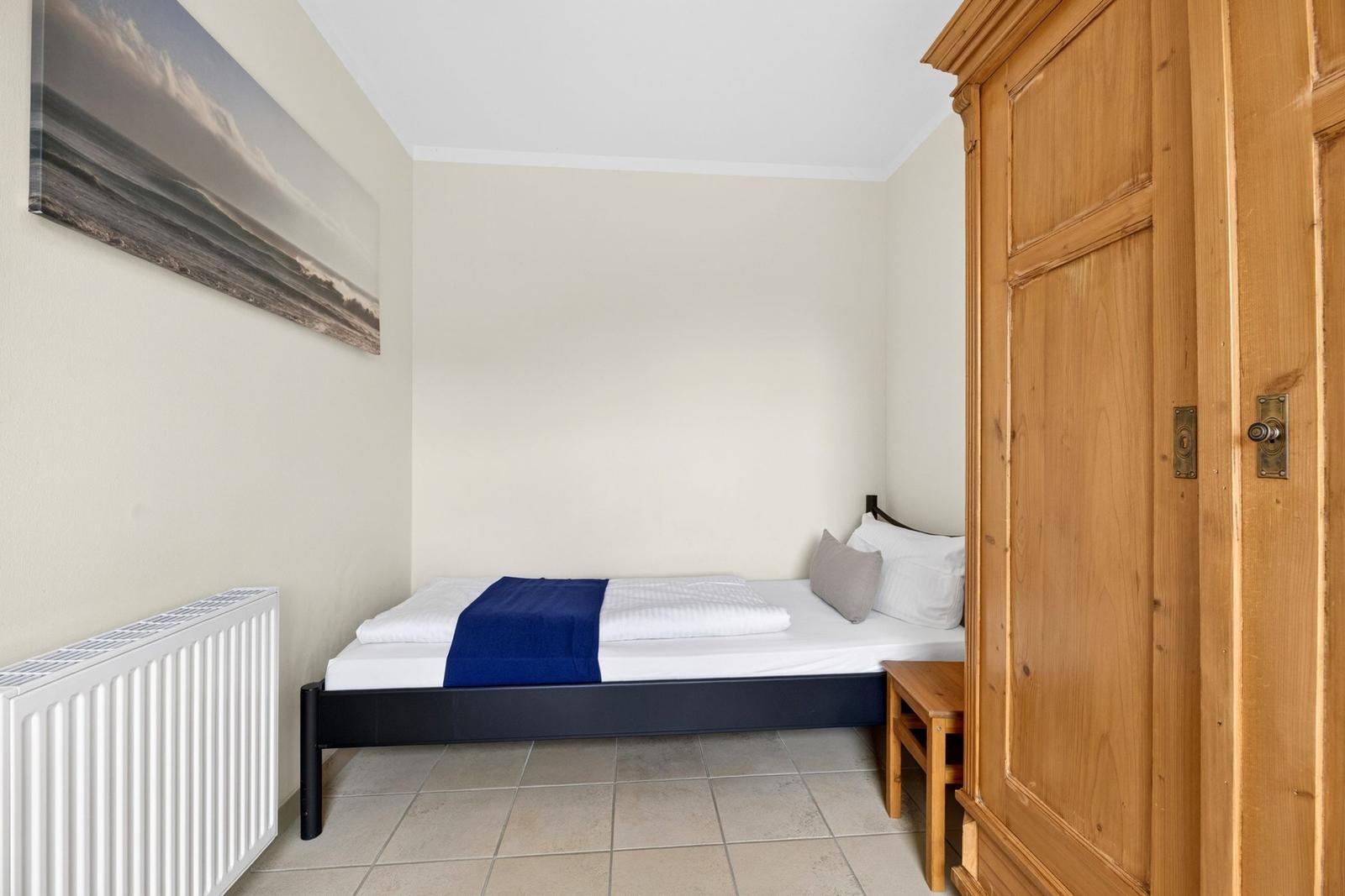 Schlafzimmer mit Bett, Kleiderschrank und Wandbild.