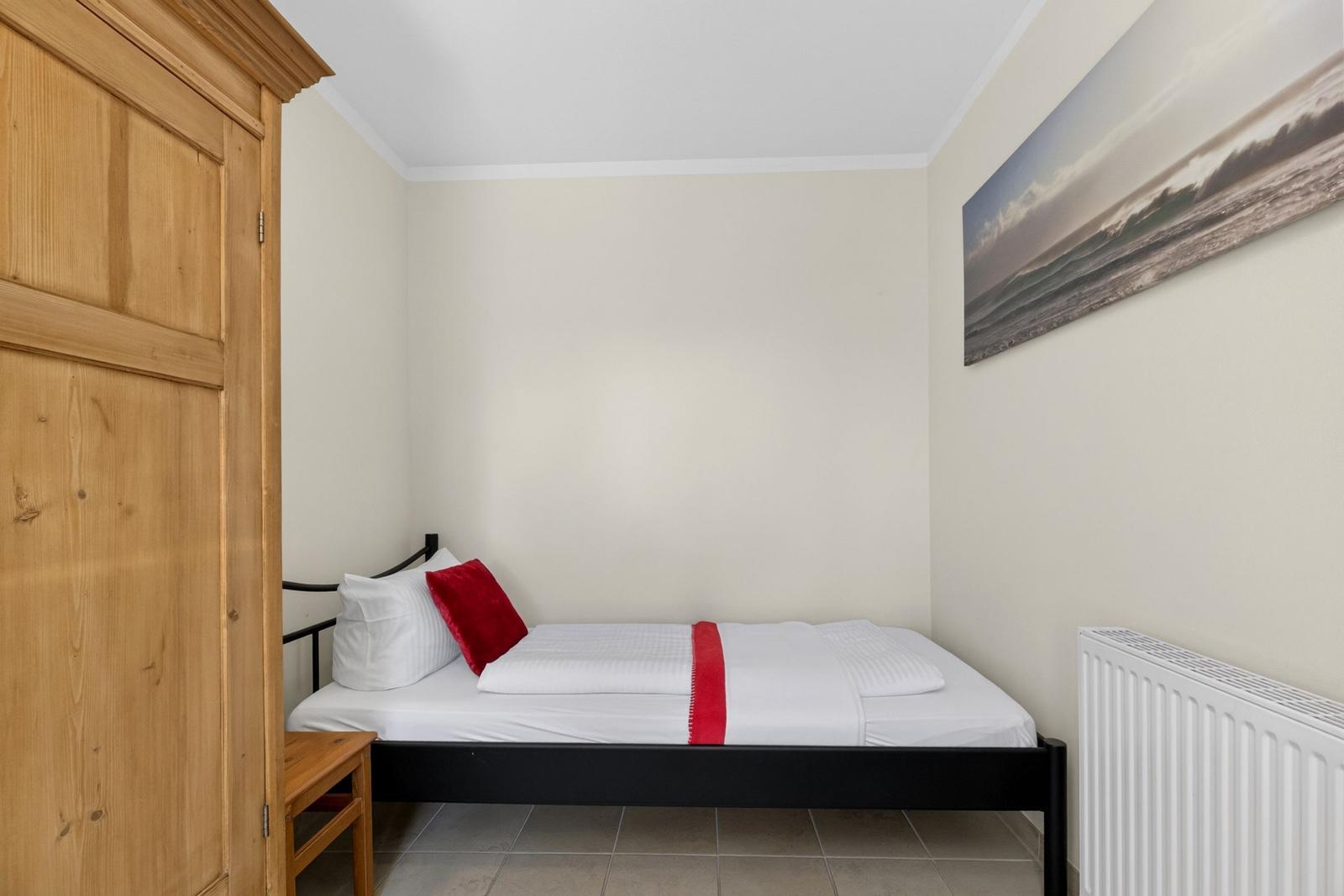 Ein Schlafzimmer mit einem Bett, einem Holzschrank und einer Wanddekoration.