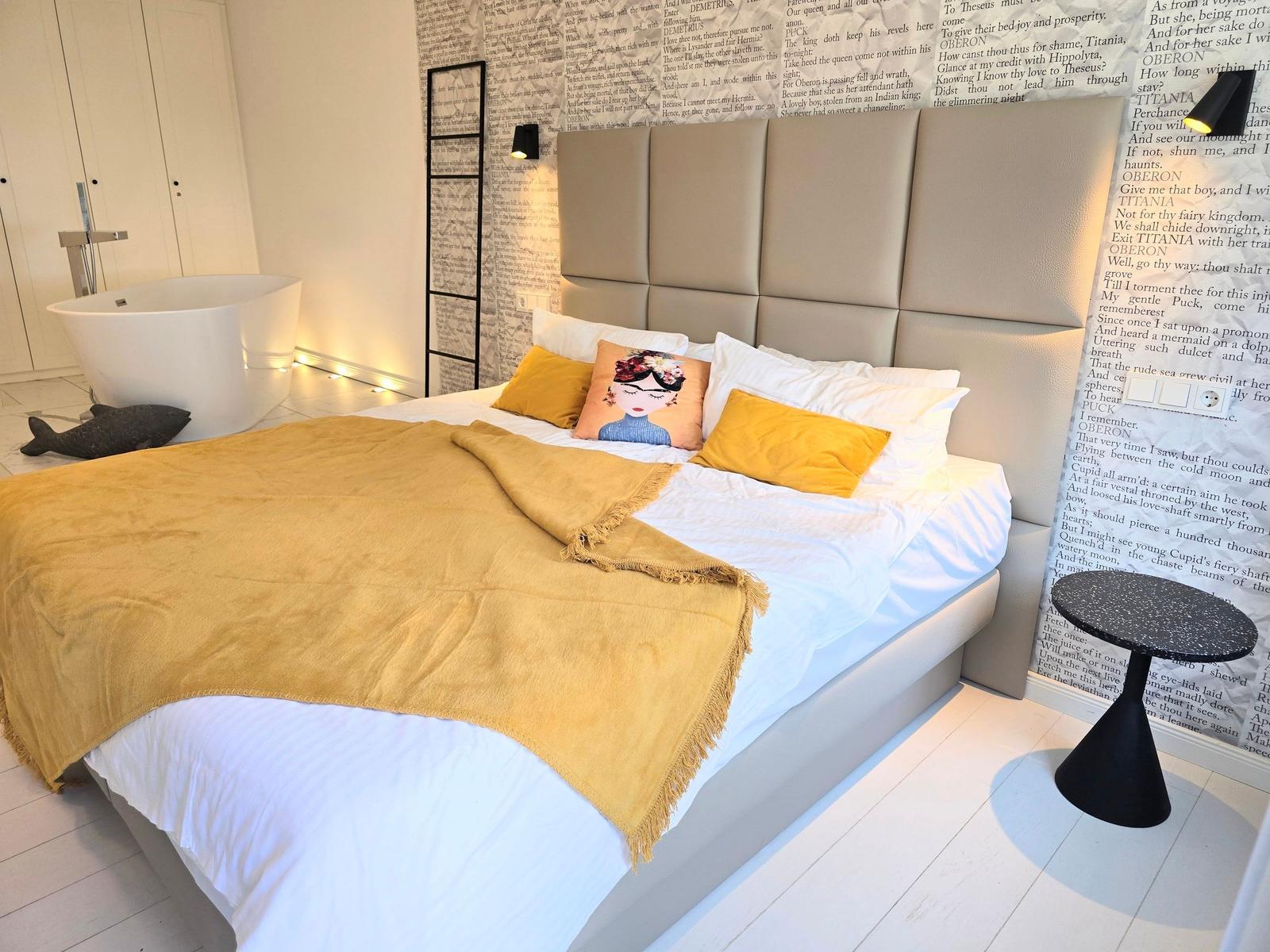 Schlafzimmer mit Bett, Badewanne und Wand mit Texten.